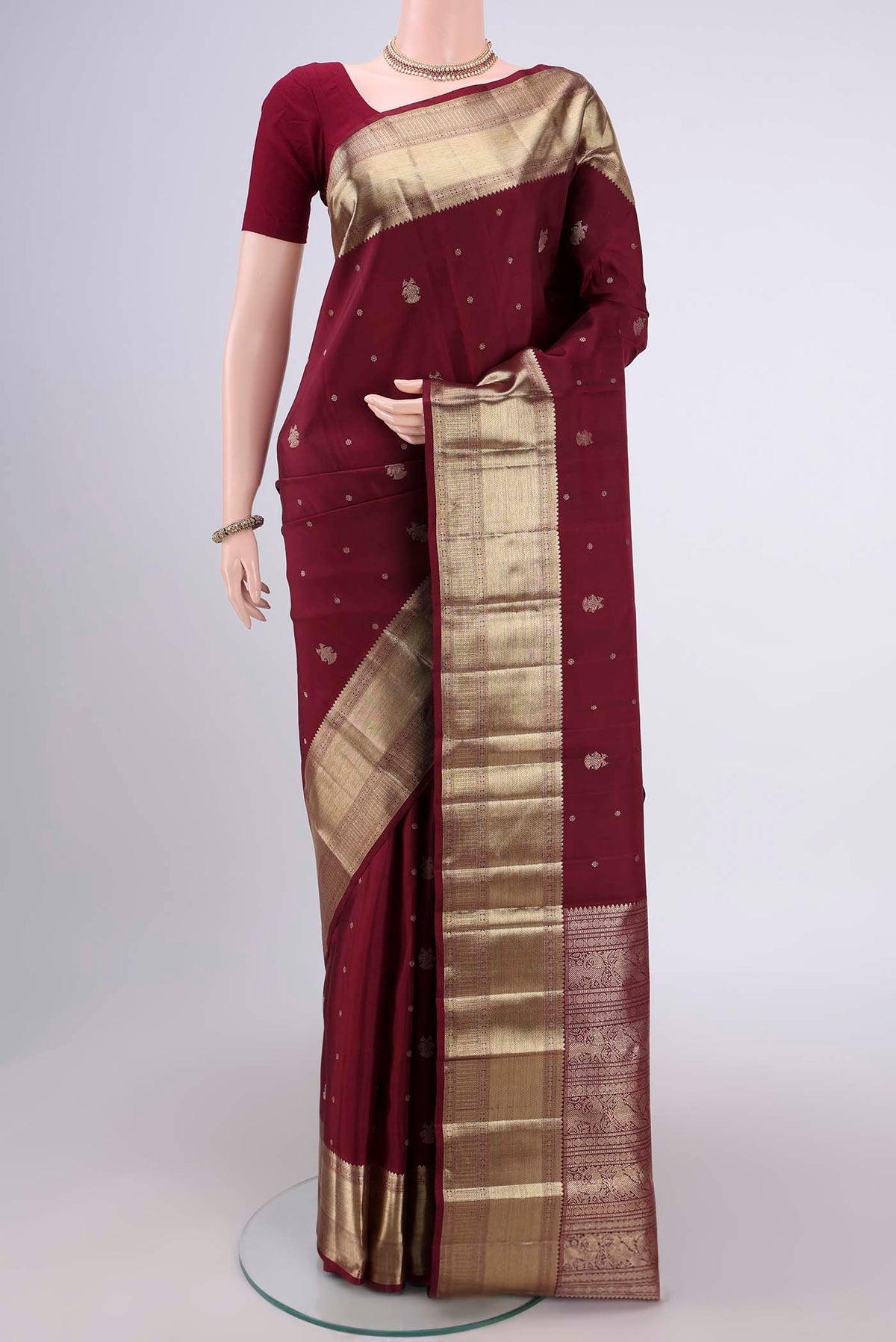 Maroon Kanjivaram Silk Saree with Zari Butta on the body and Zari Border.  displayed on a mannequin