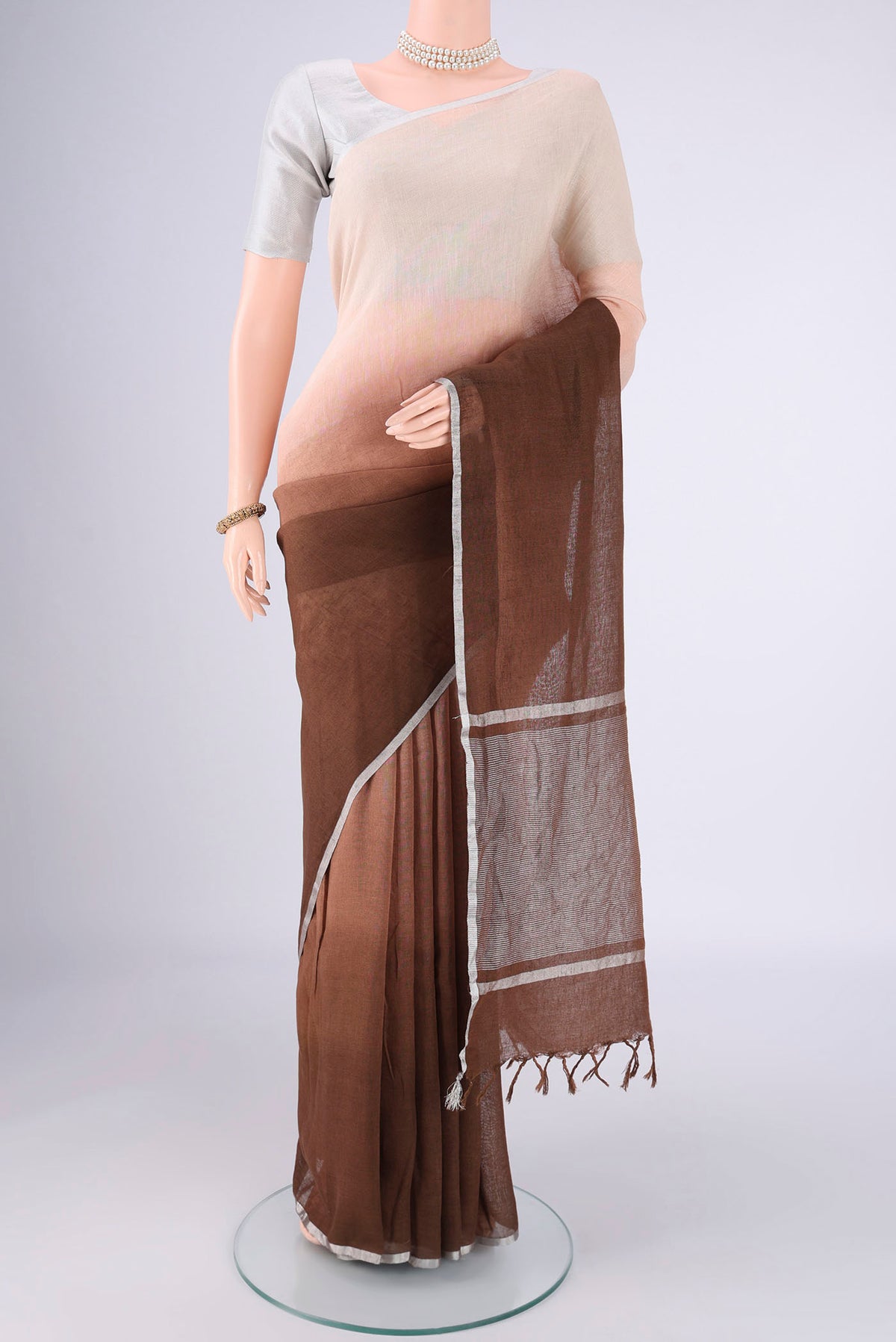 Brown Linen Saree with Half And Half on the body and Thin Zari Line.  displayed on a mannequin