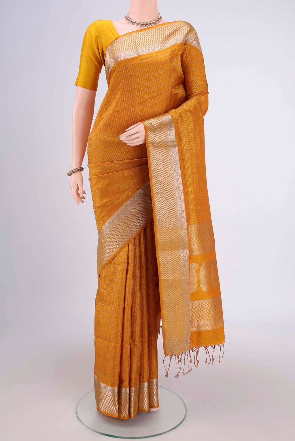 Mustard Baluchari Silk Saree with Jacquard design on the body and Zari Border.  displayed on a mannequin