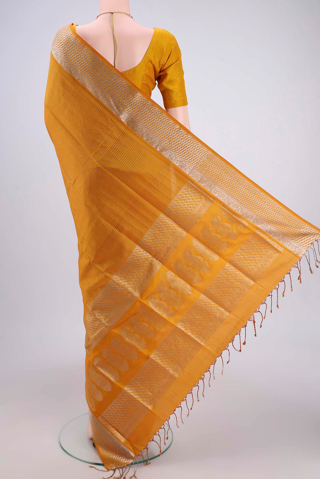 Flat view of Mustard Baluchari Silk Saree with Jacquard design on the body and Zari Border. 