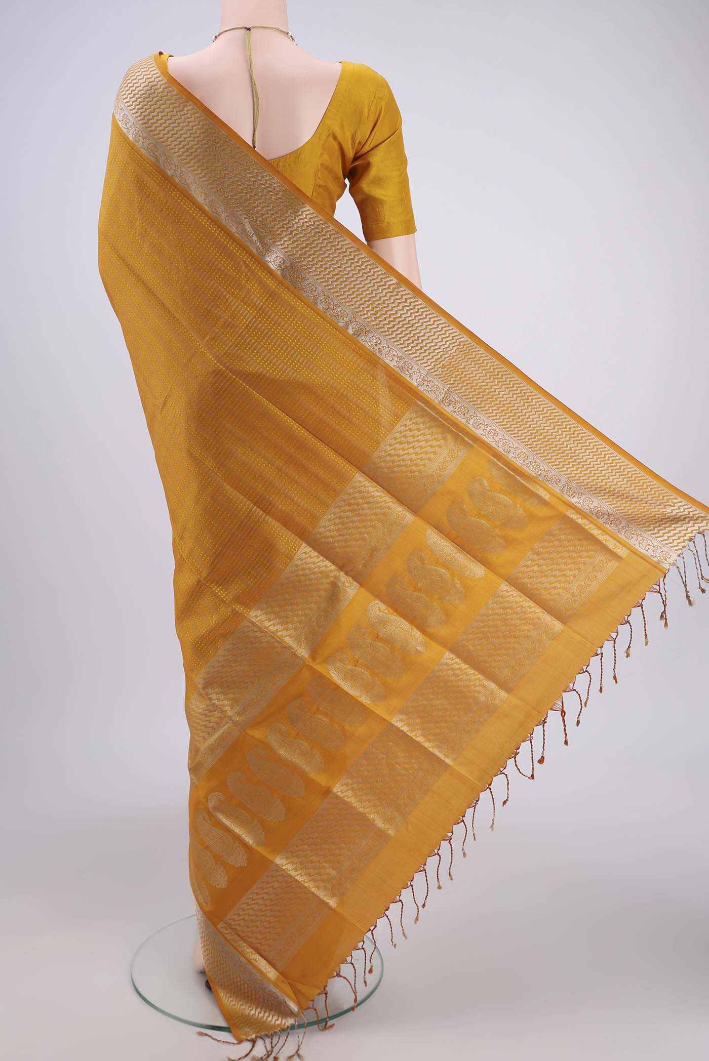 Flat view of Mustard Baluchari Silk Saree with Jacquard design on the body and Zari Border. 
