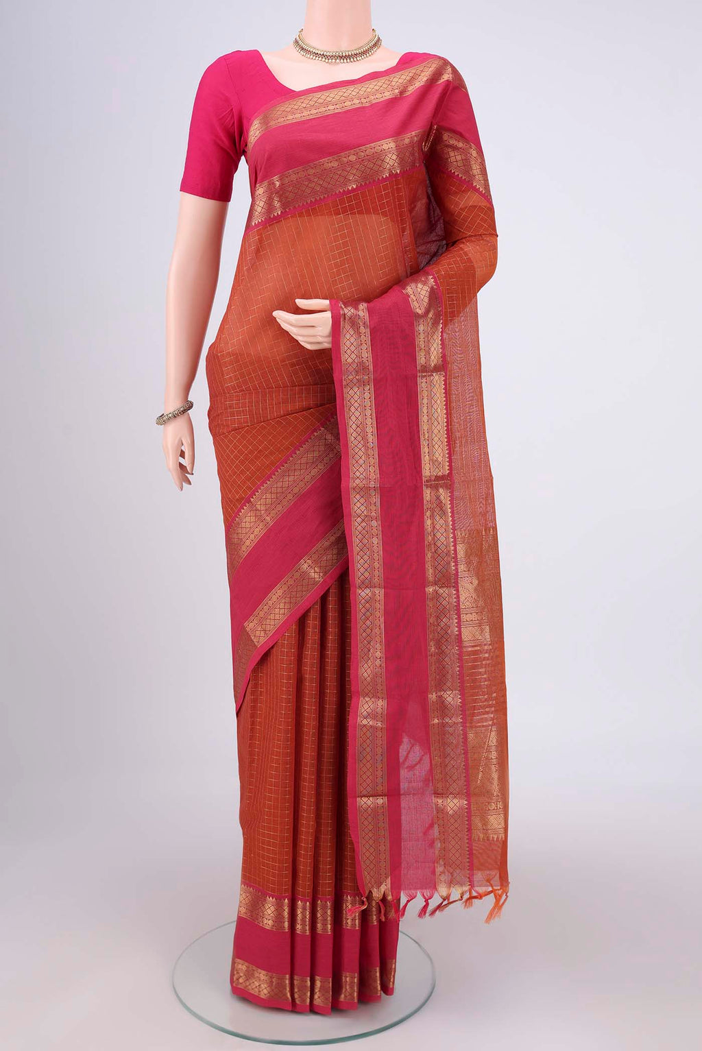 Rust Kanchi Cotton Saree with Checked design on the body and Zari Border.  displayed on a mannequin