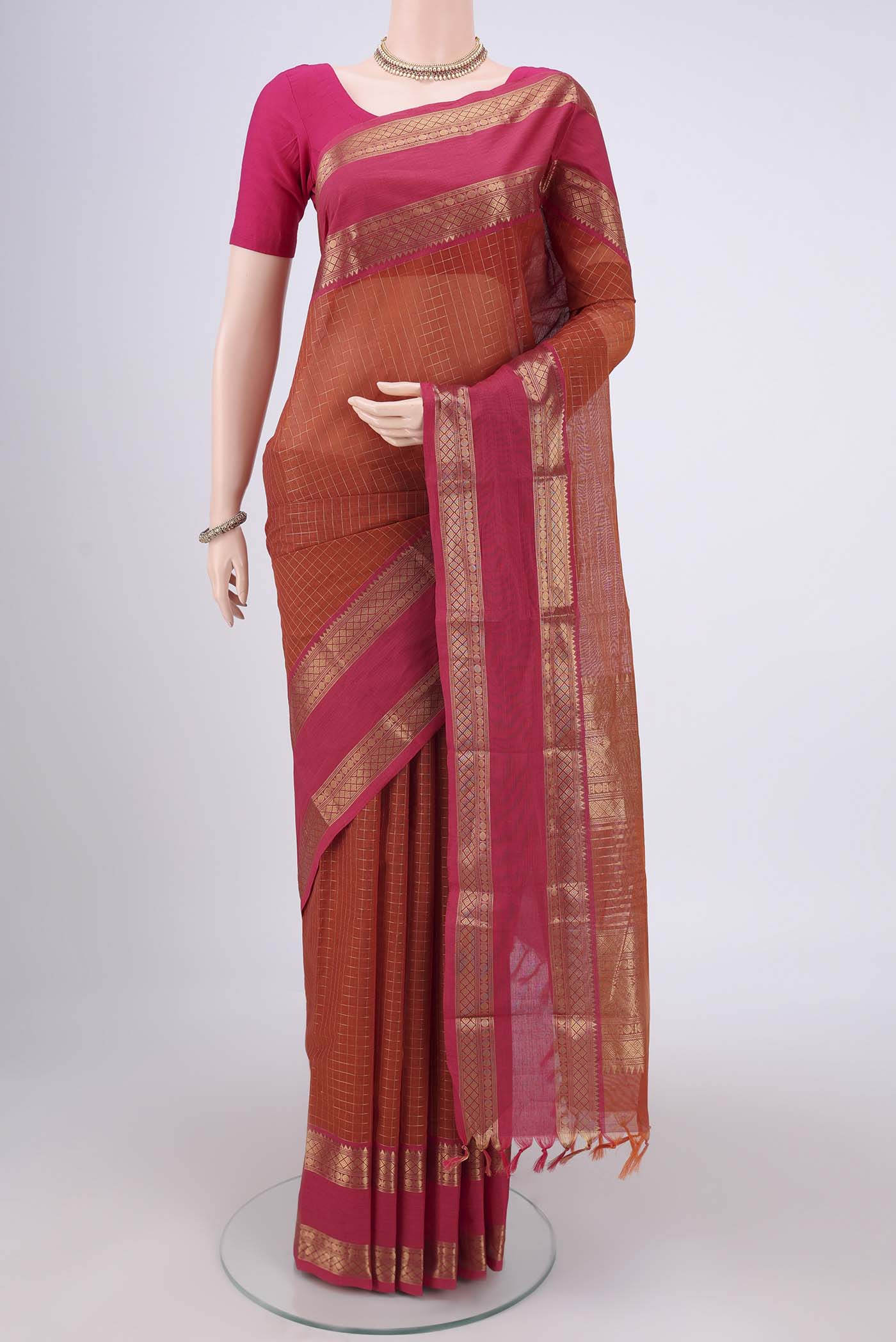 Rust Kanchi Cotton Saree with Checked design on the body and Zari Border.  displayed on a mannequin