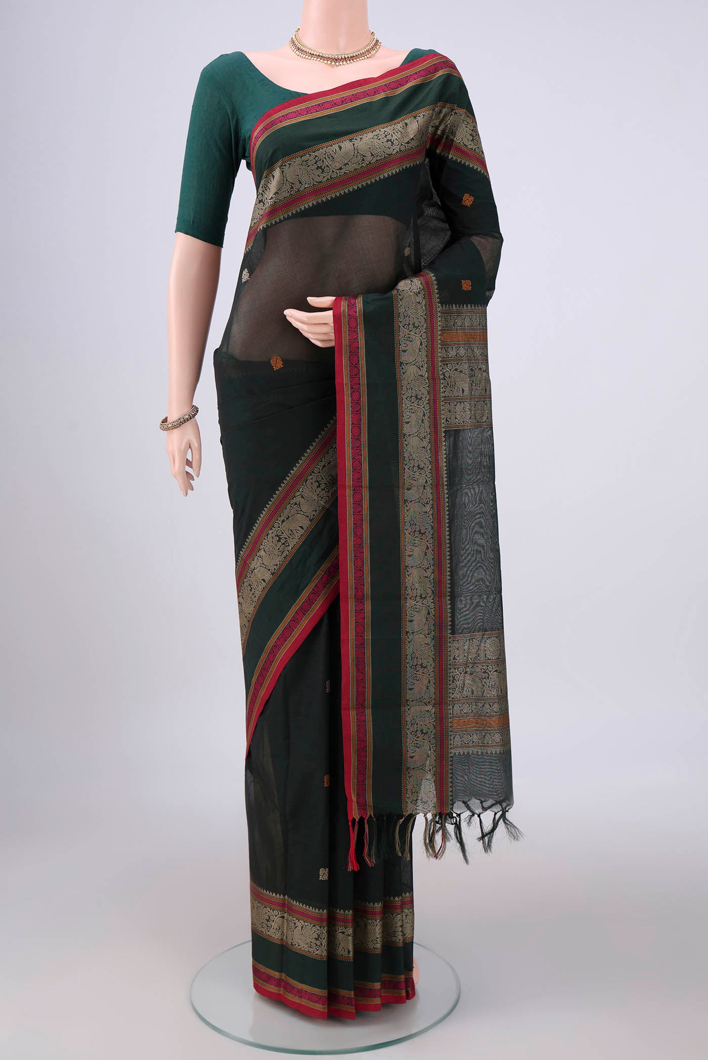Bottle Green Kanchi Cotton Saree with Plain Body and Thread Border.  displayed on a mannequin