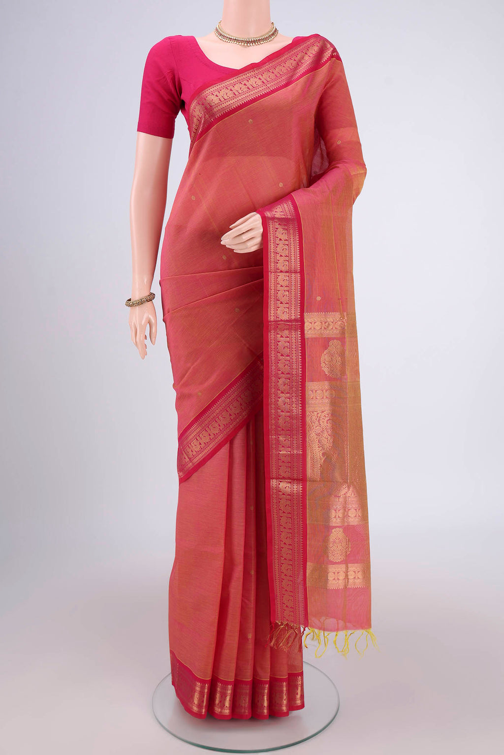 Peach Kanjivaram Saree with Zari Butta on the body and Zari Border.  displayed on a mannequin
