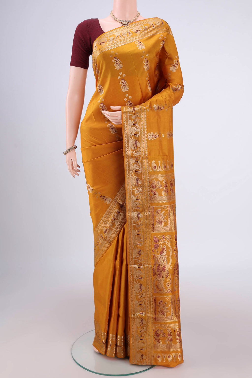 Mustard Baluchari Silk Saree with Zari And Thread Butta on the body and Zari And Thread Border.  displayed on a mannequin