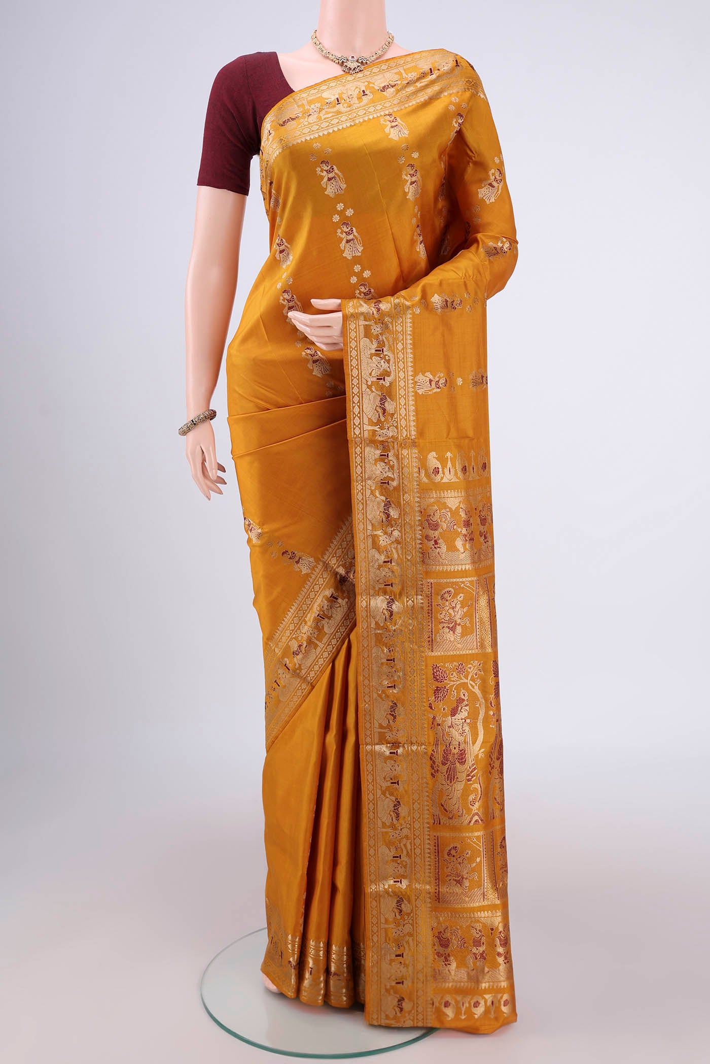 Mustard Baluchari Silk Saree with Zari And Thread Butta on the body and Zari And Thread Border.  displayed on a mannequin