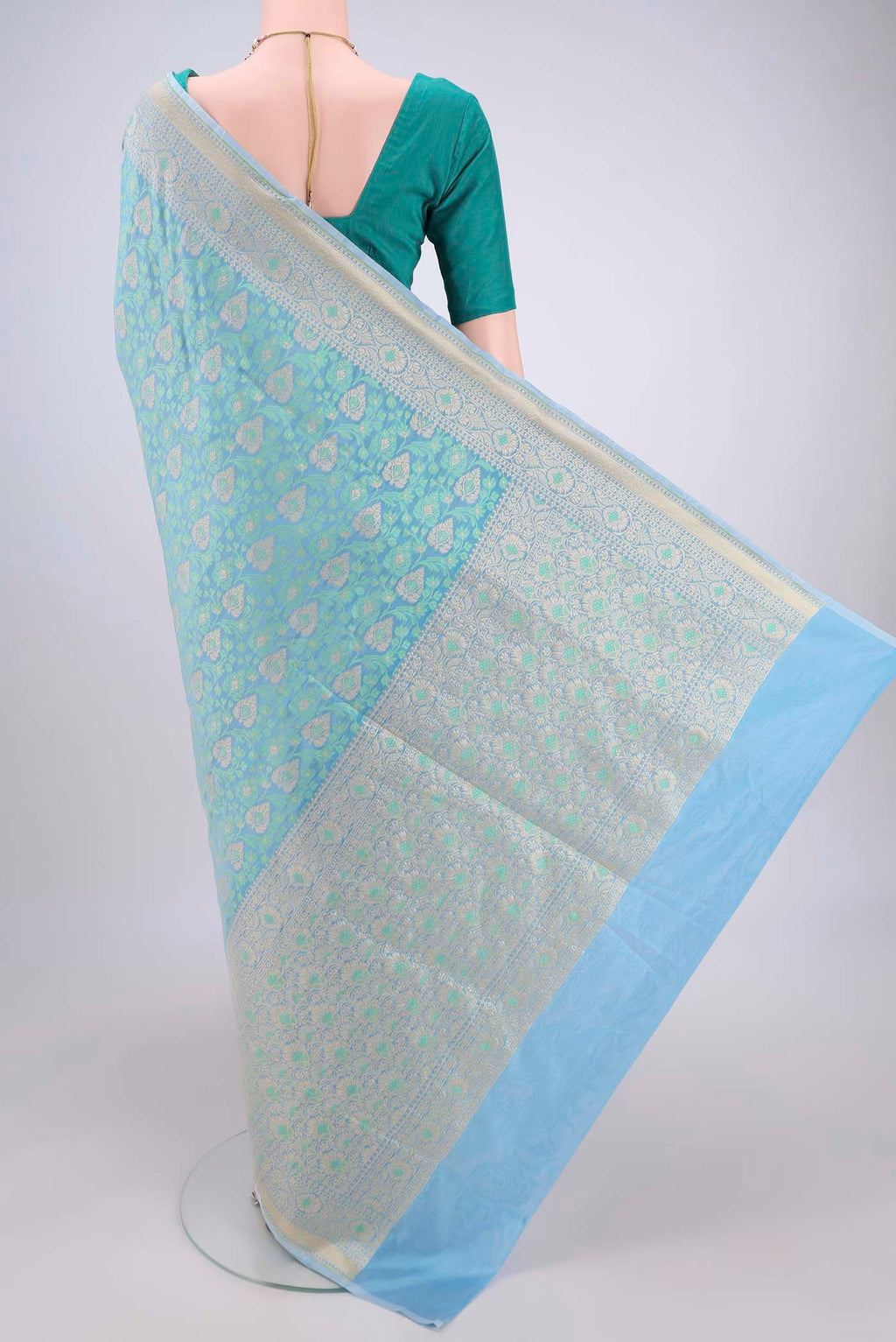 Flat view of Sky Blue Banarasi Silk Saree with Zari And Thread Butta on the body and Zari Border. 