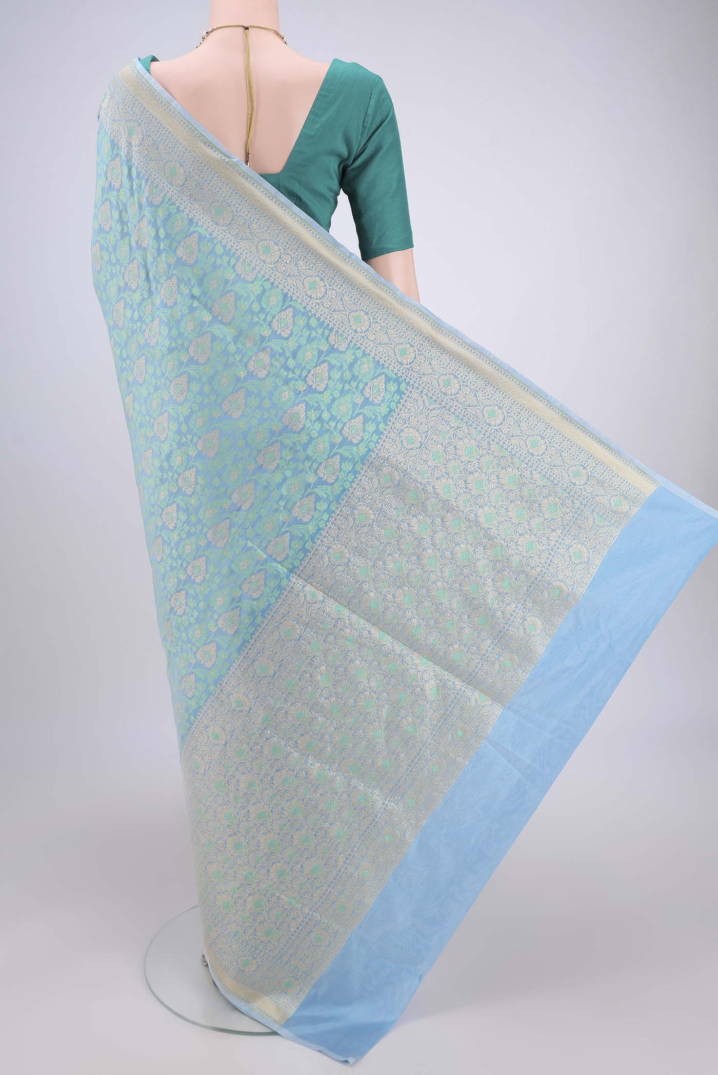 Flat view of Sky Blue Banarasi Silk Saree with Zari And Thread Butta on the body and Zari Border. 