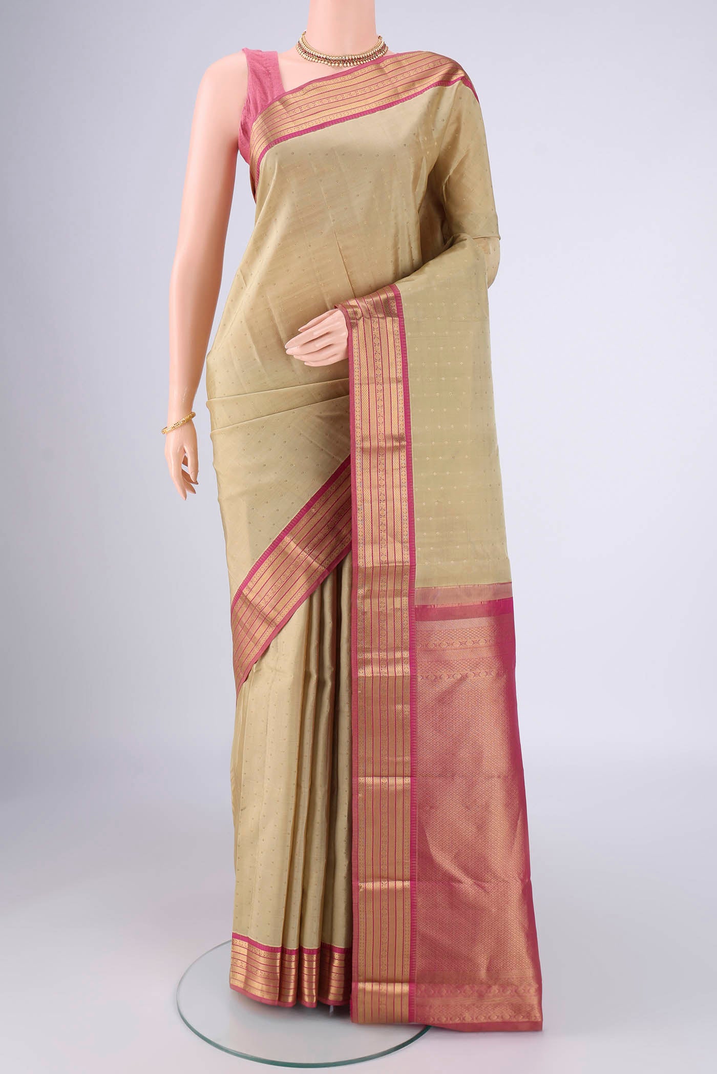 Beige Kanchipuram Silk Saree with Zari Butta on the body and Zari Border.  displayed on a mannequin