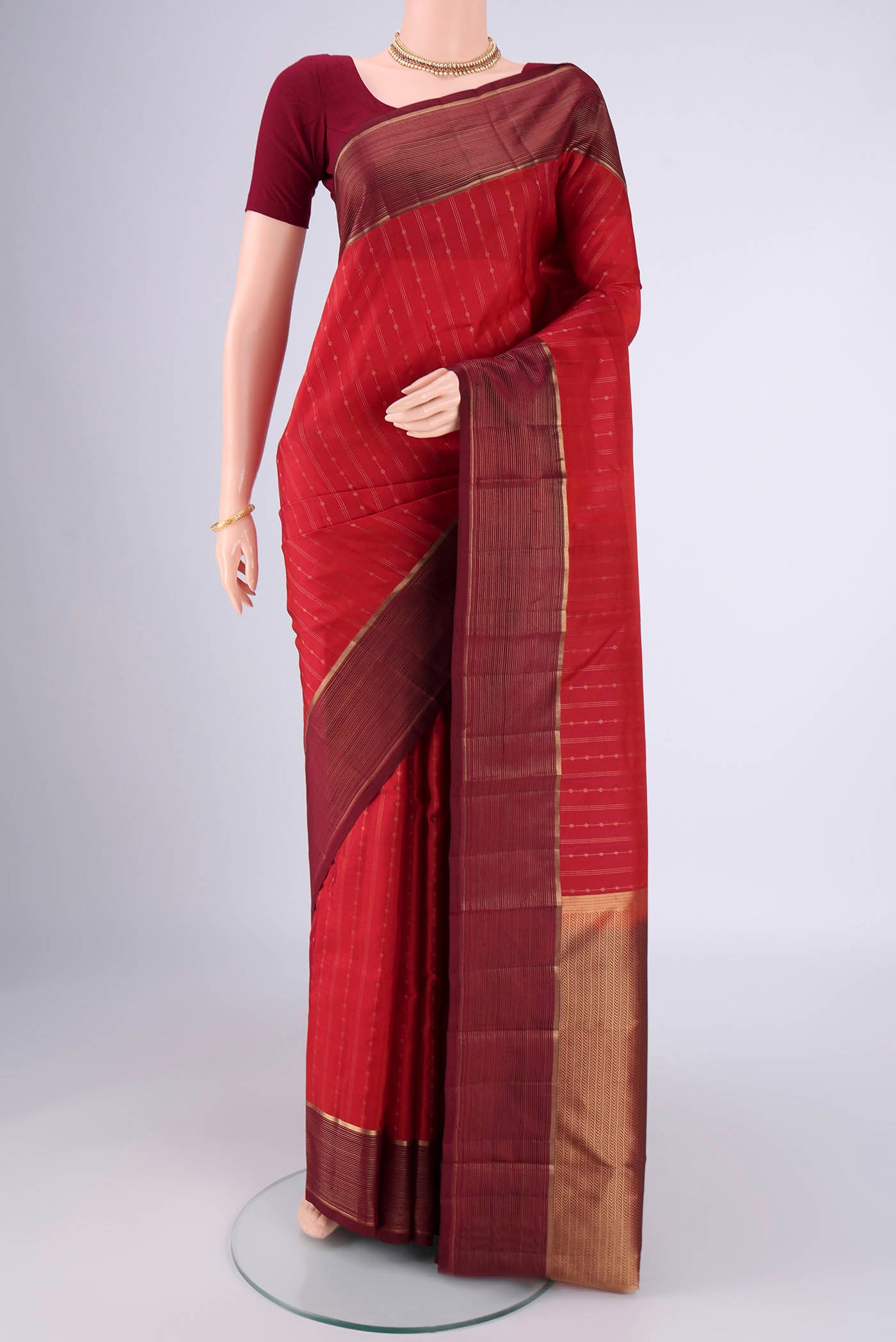 Red Kanchipuram Silk Saree with Stripes on the body and Zari Border.  displayed on a mannequin