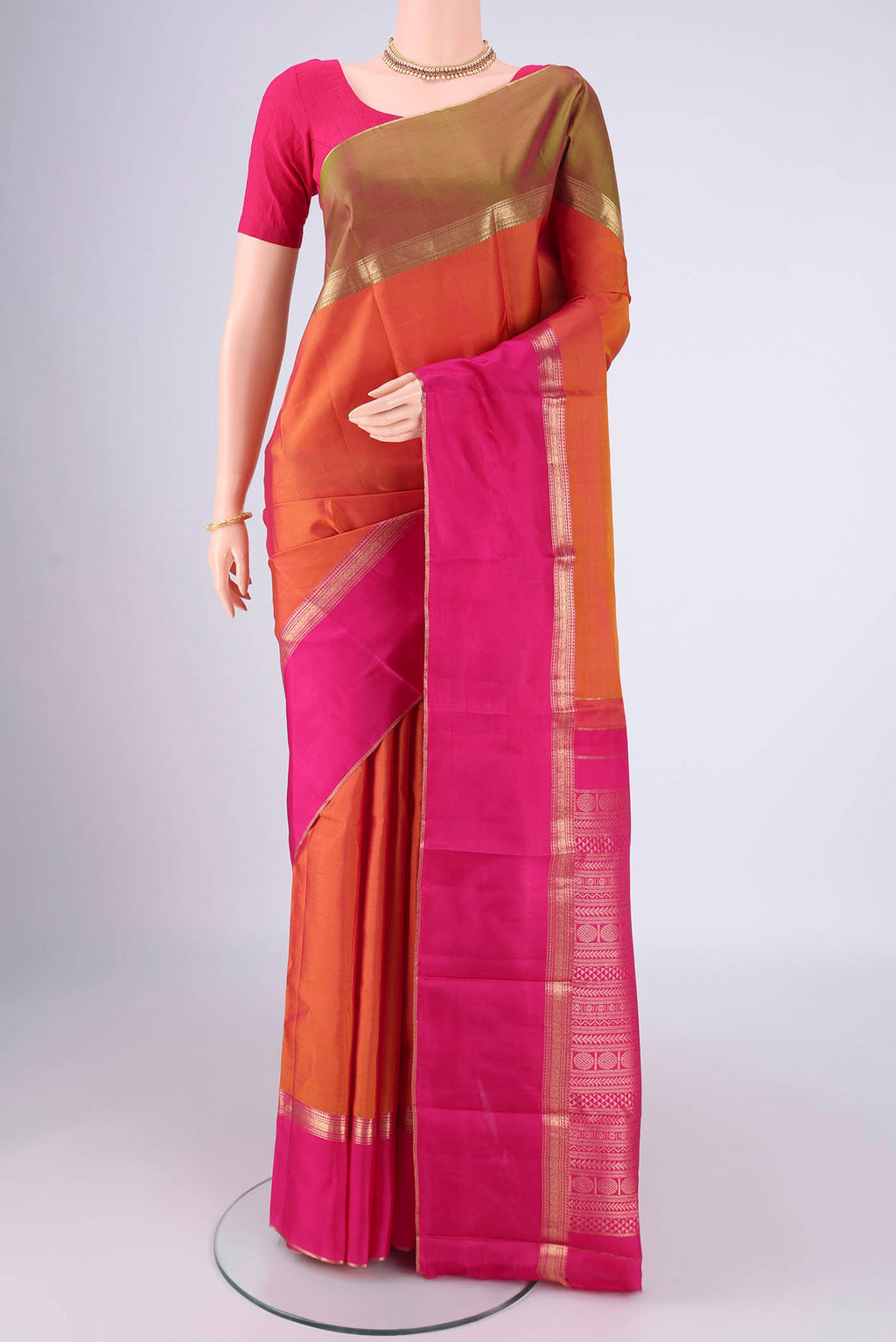 Brick Orange Dual Tone Kanchipuram Silk Saree with Zari Butta on the body and Ganga Jamuna Border.  displayed on a mannequin