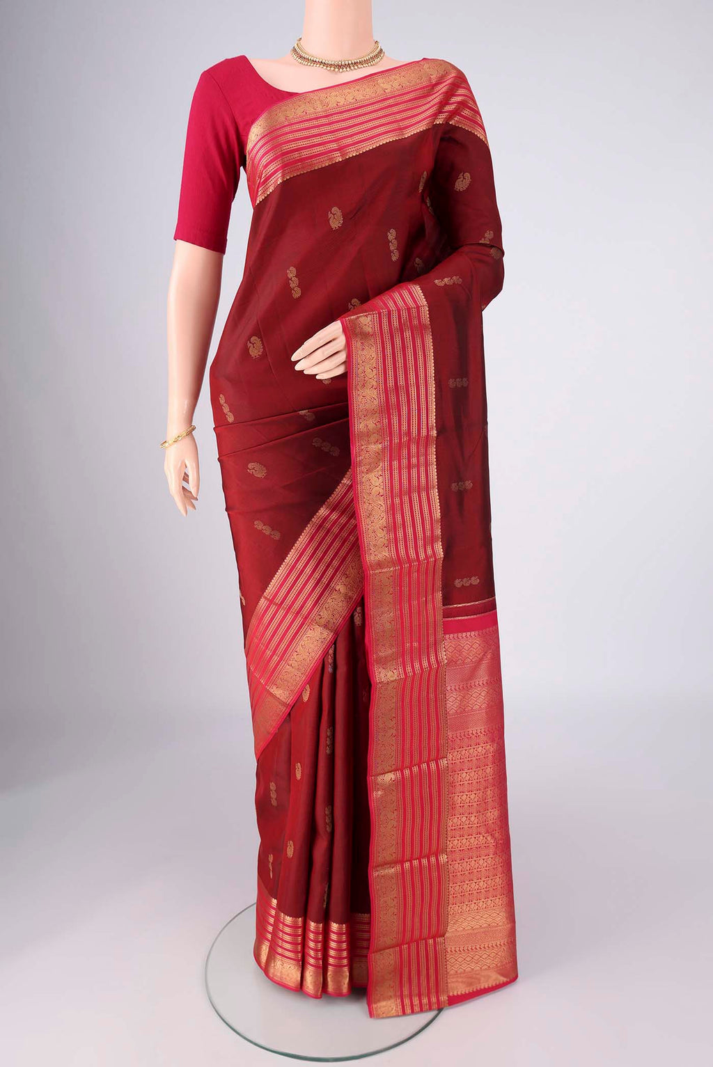 Maroon Kanchipuram Silk Saree with Zari Butta on the body and Zari Border.  displayed on a mannequin