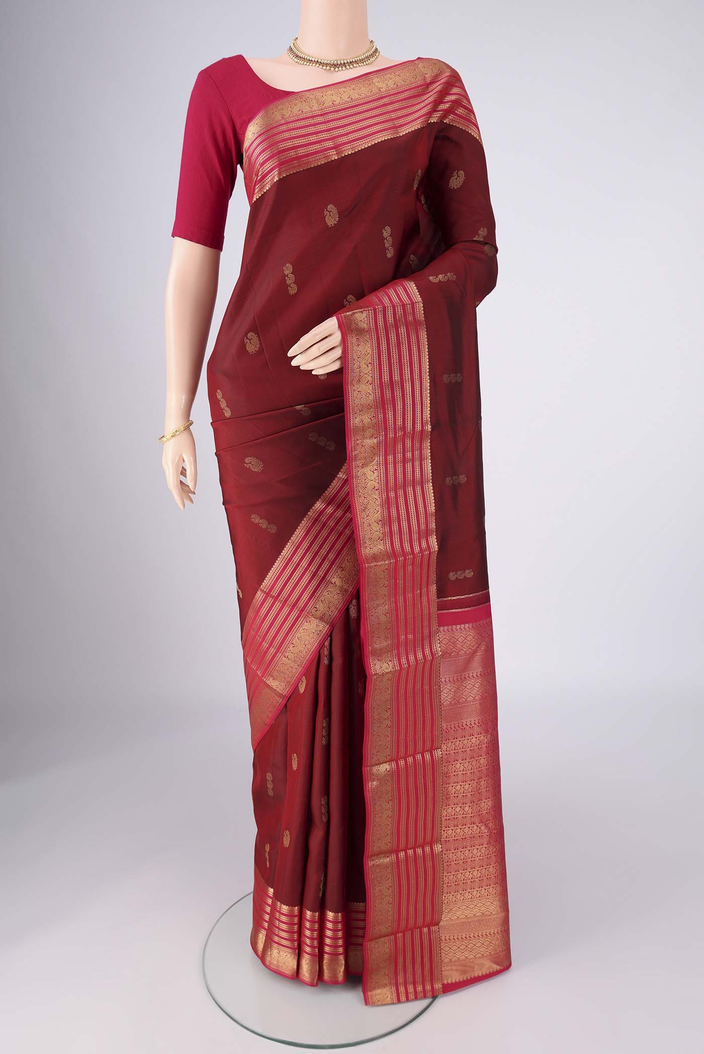 Maroon Kanchipuram Silk Saree with Zari Butta on the body and Zari Border.  displayed on a mannequin
