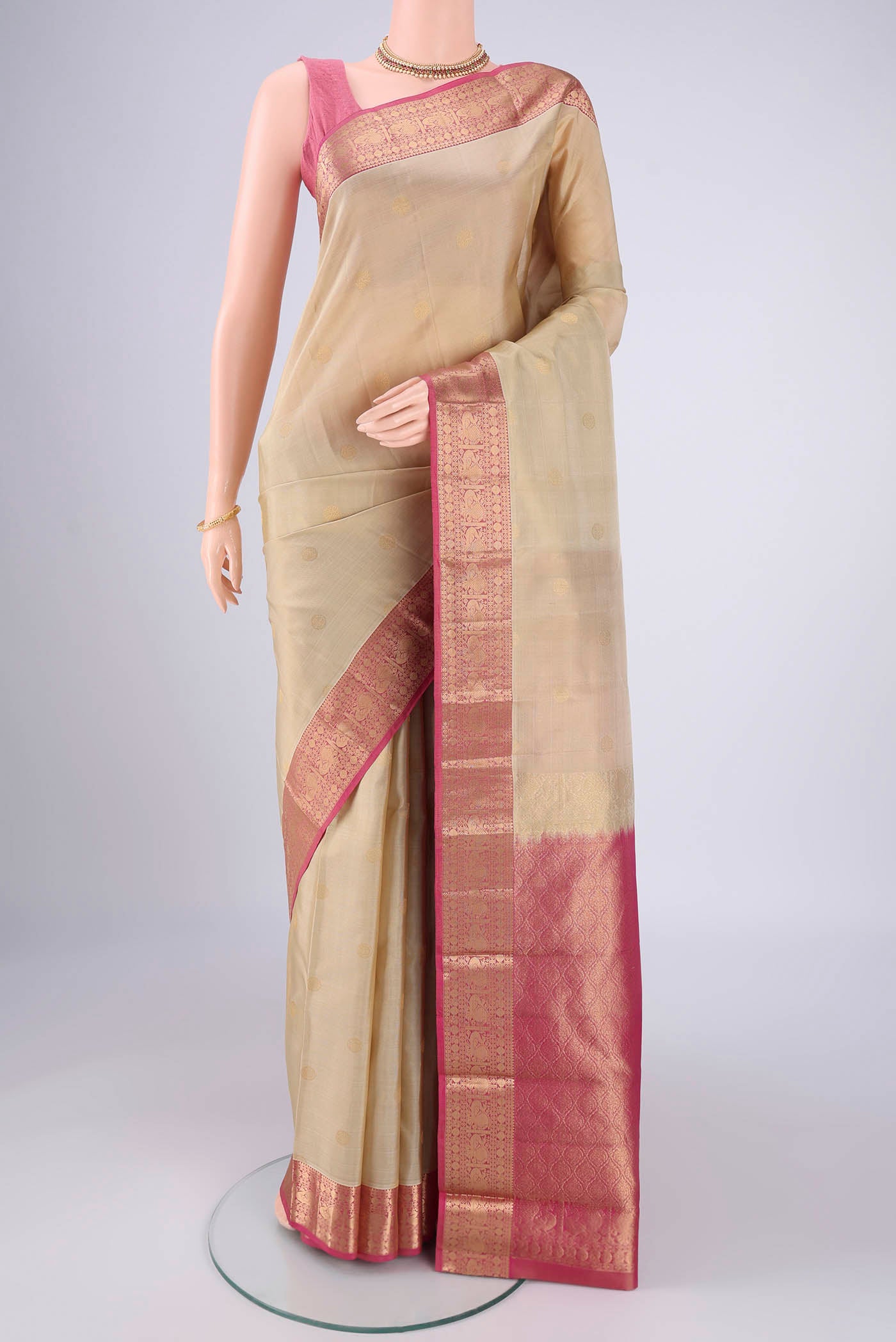 Beige Kanchipuram Silk Saree with Zari Butta on the body and Zari Border.  displayed on a mannequin