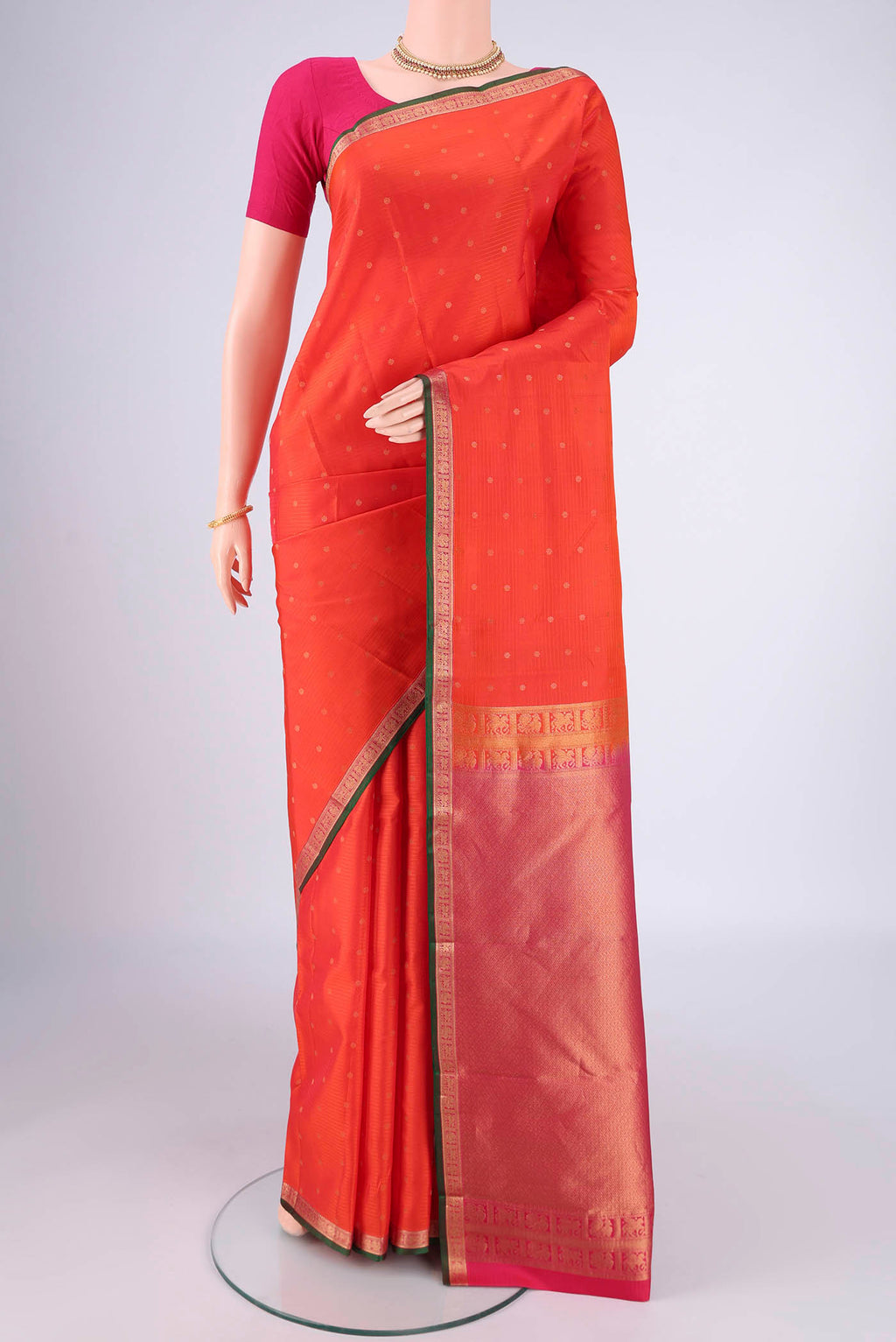 Orange Kanjivaram Silk Saree with Zari Butta on the body and Zari Border.  displayed on a mannequin