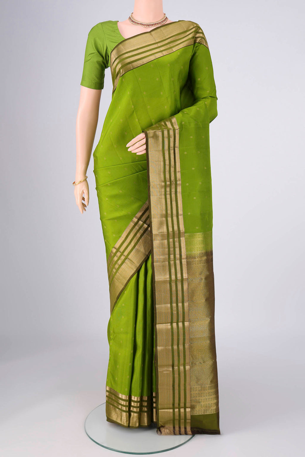Green Kanchipuram Silk Saree with Zari Butta on the body and Zari Border.  displayed on a mannequin