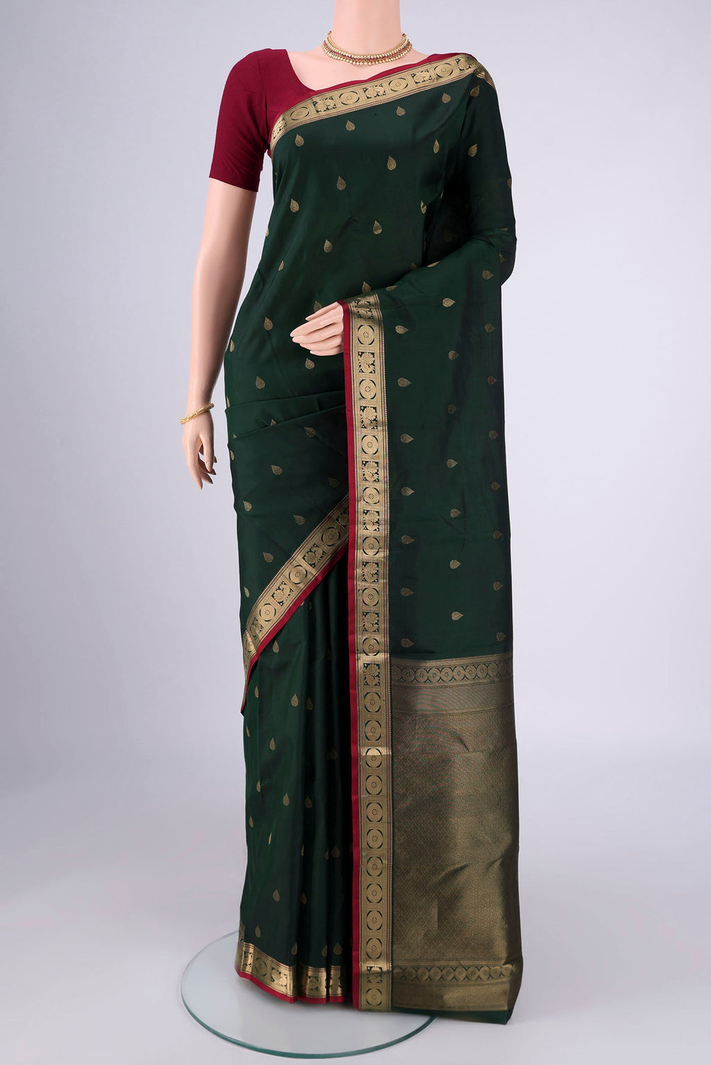 Bottle Green Kanchipuram Silk Saree with Zari Butta on the body and Zari Border.  displayed on a mannequin