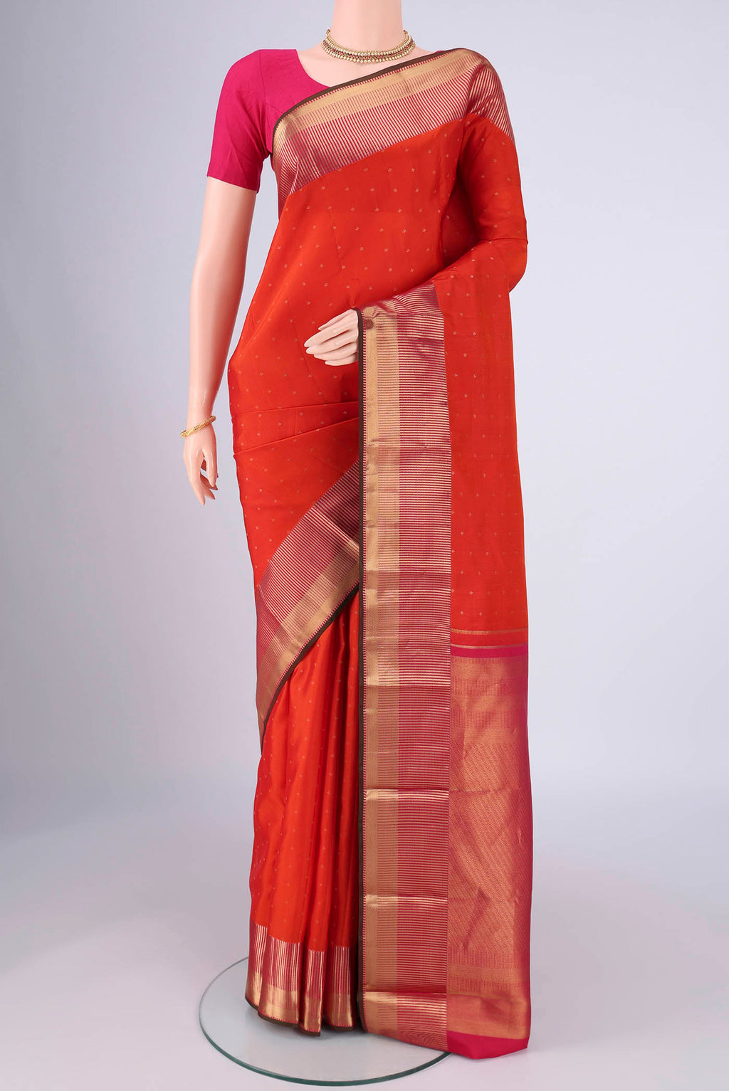 Orange Kanchipuram Silk Saree with Zari Butta on the body and Zari Border.  displayed on a mannequin