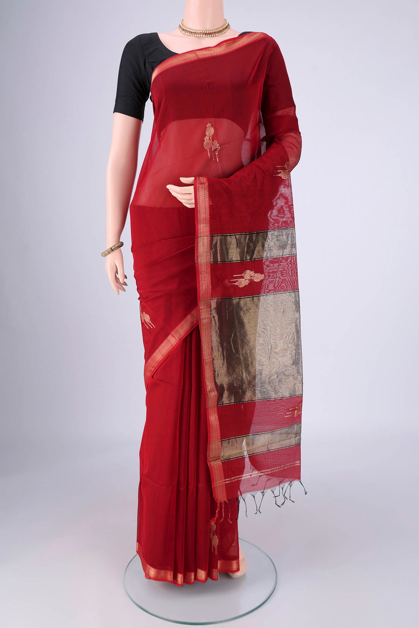 Maroon Maheshwari Silk Cotton Saree with Zari Butta on the body and Zari Border.  displayed on a mannequin