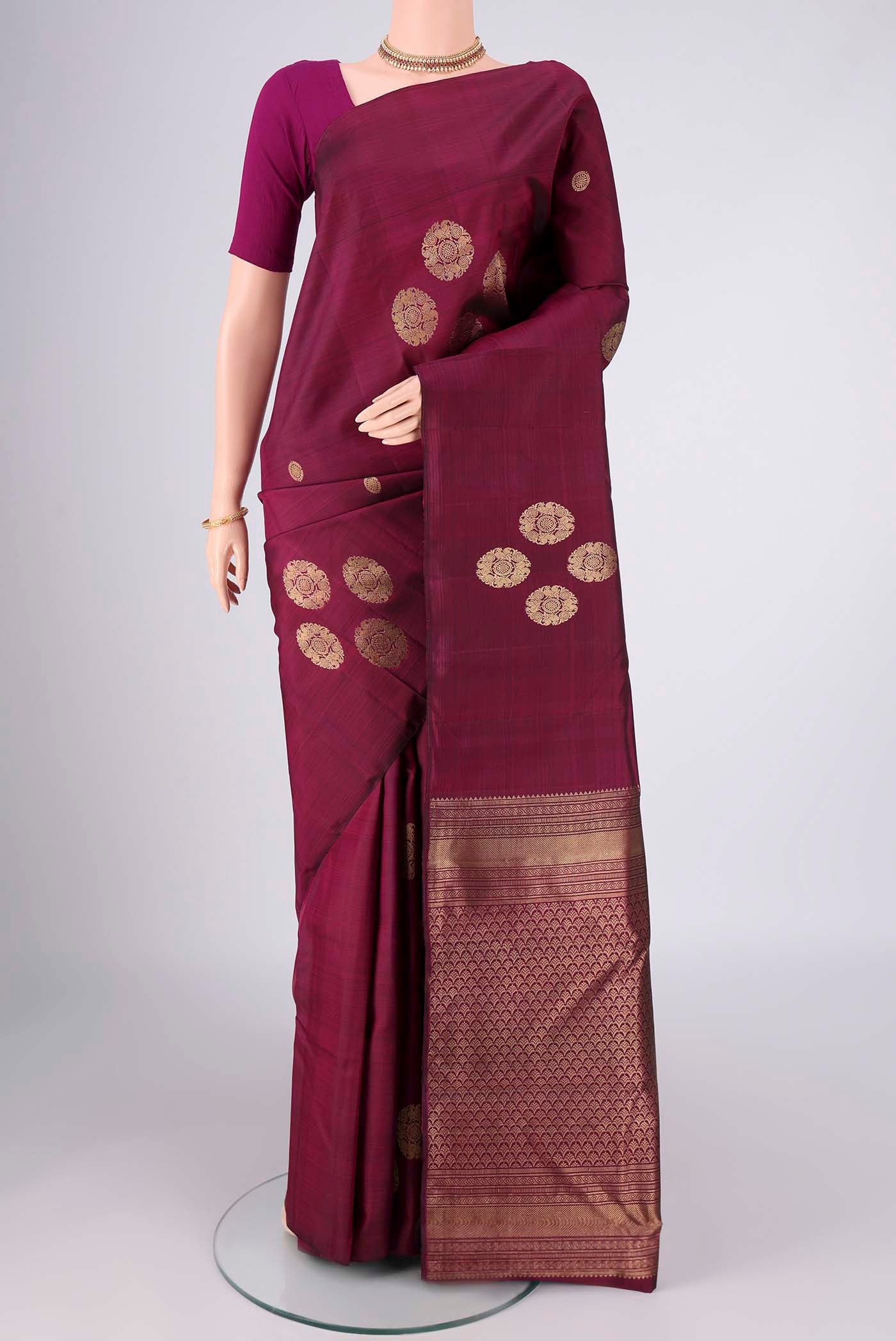 Maroon Kanchipuram Silk Saree with Zari Butta on the body and Without Border.  displayed on a mannequin
