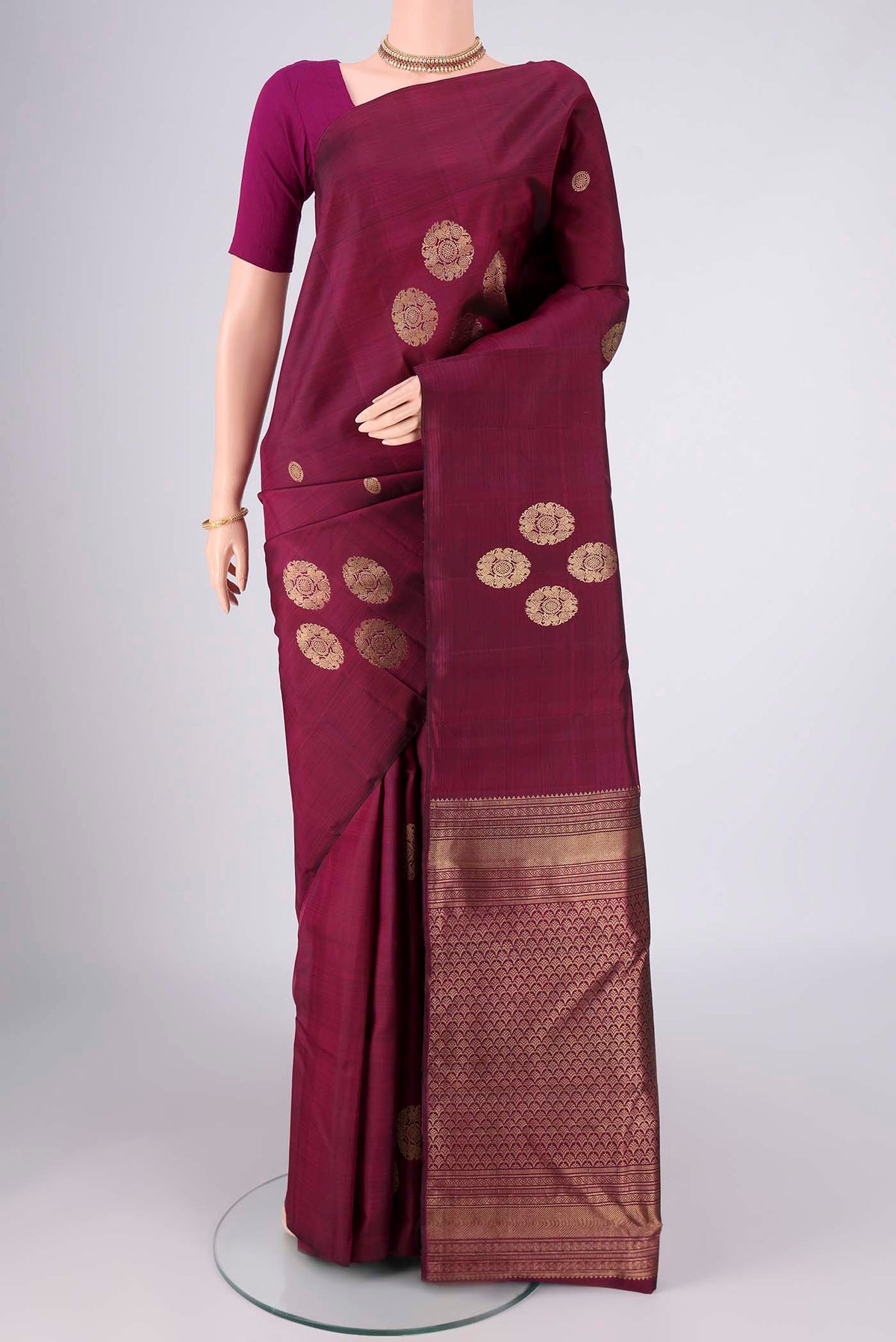Maroon Kanchipuram Silk Saree with Zari Butta on the body and Without Border.  displayed on a mannequin