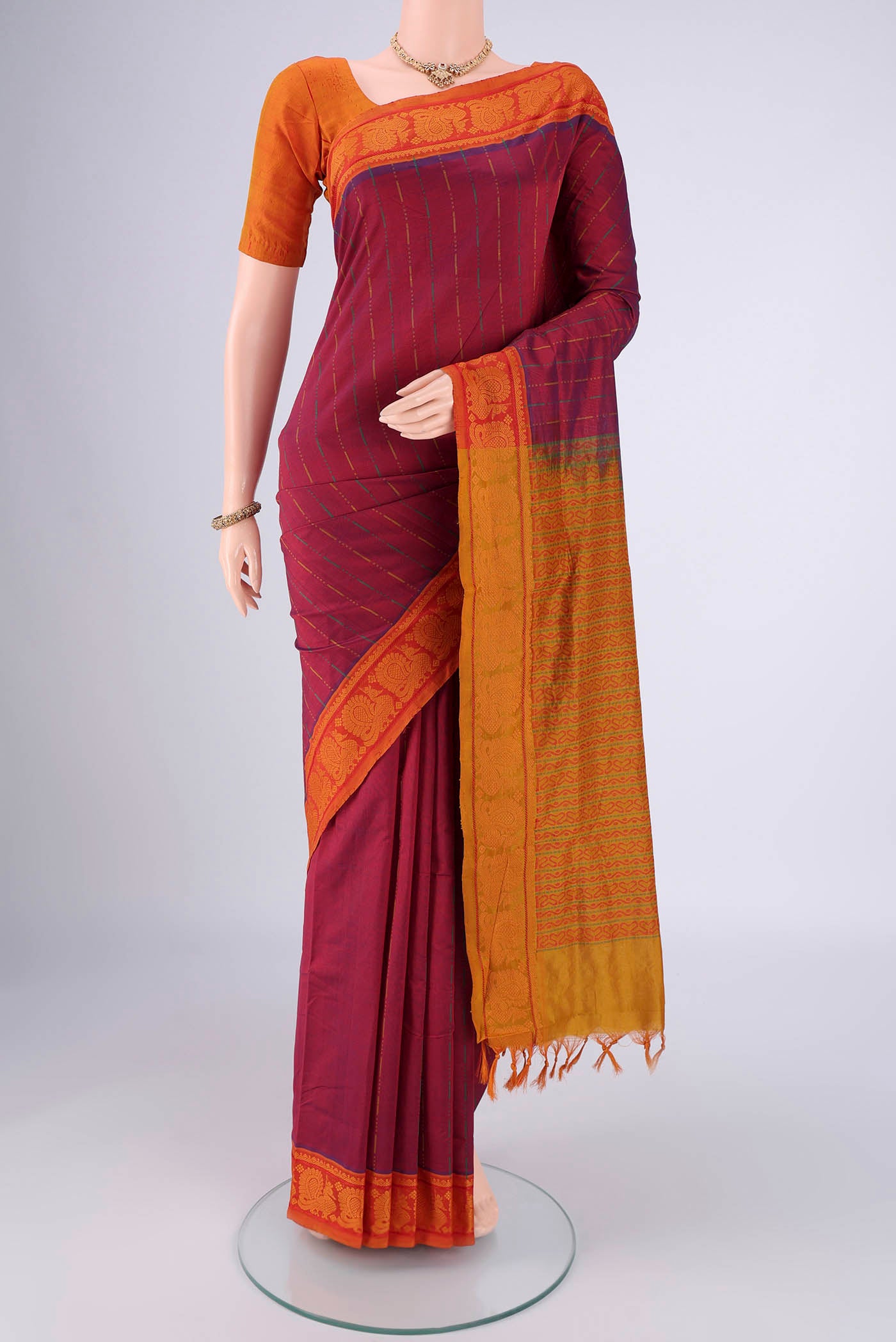 Magenta Blended Poly Cotton Saree with Stripes on the body and Thread Border.  displayed on a mannequin