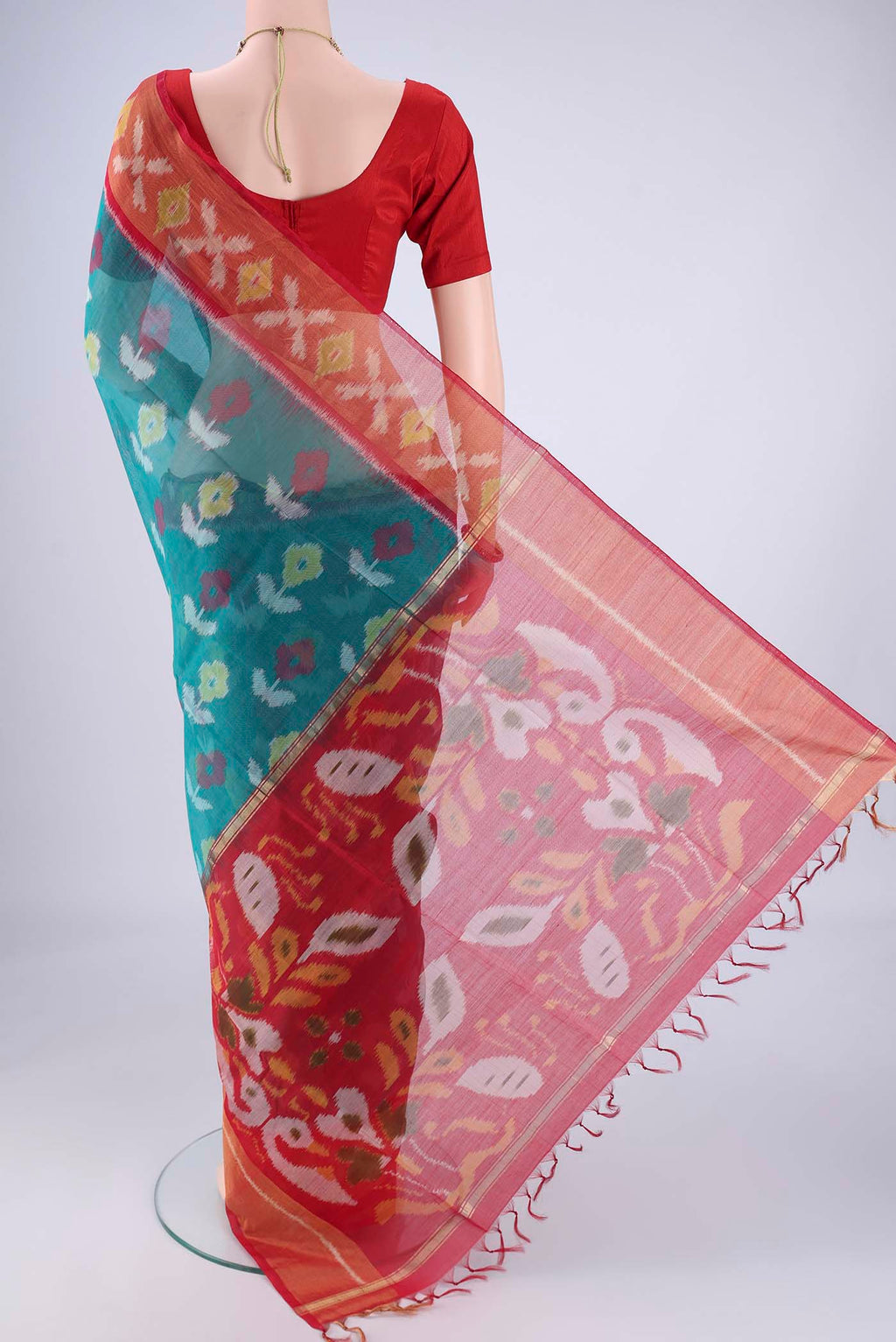 Flat view of Teal Silk Cotton Saree with Ikat design on the body and Zari Border. 