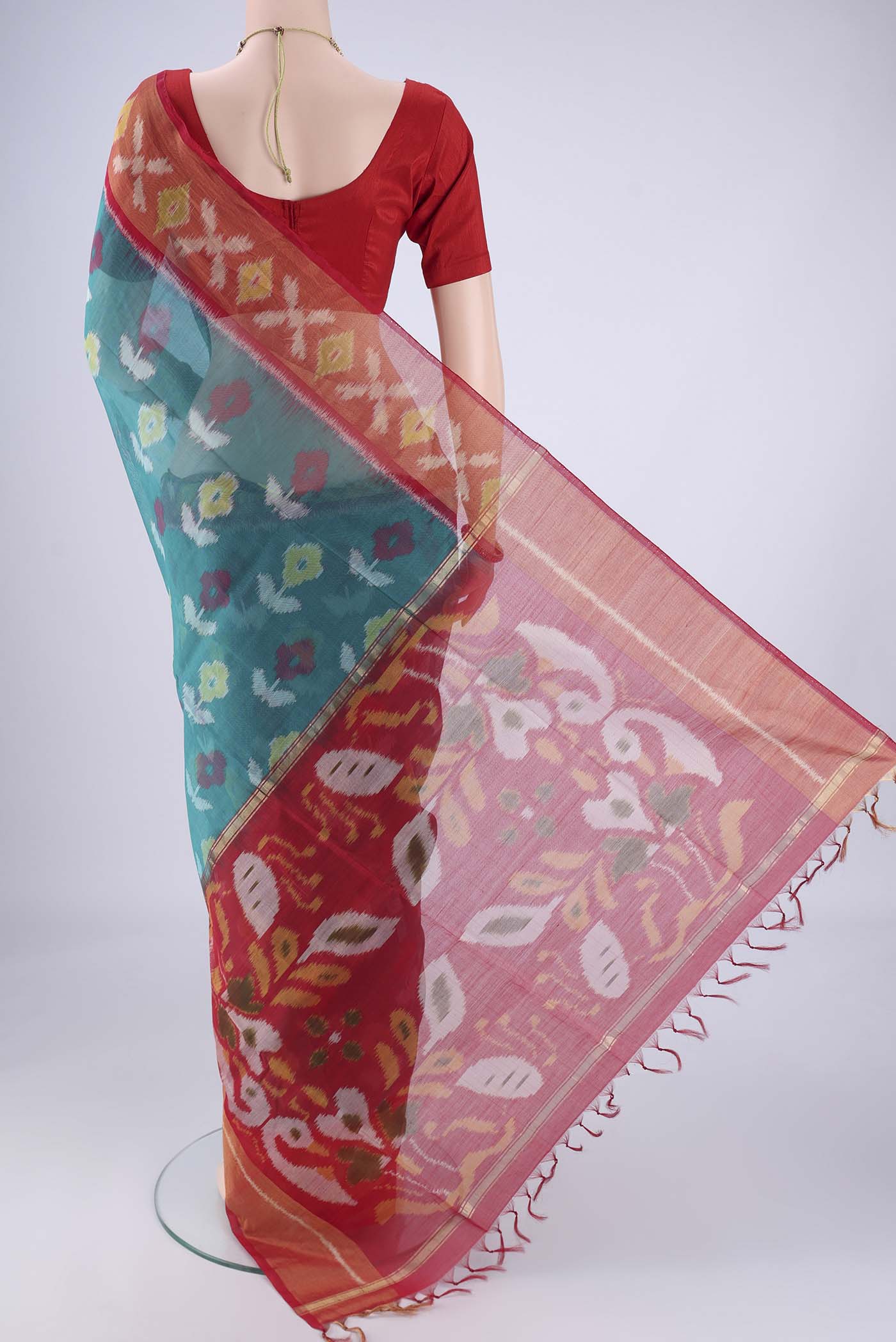Flat view of Teal Silk Cotton Saree with Ikat design on the body and Zari Border. 