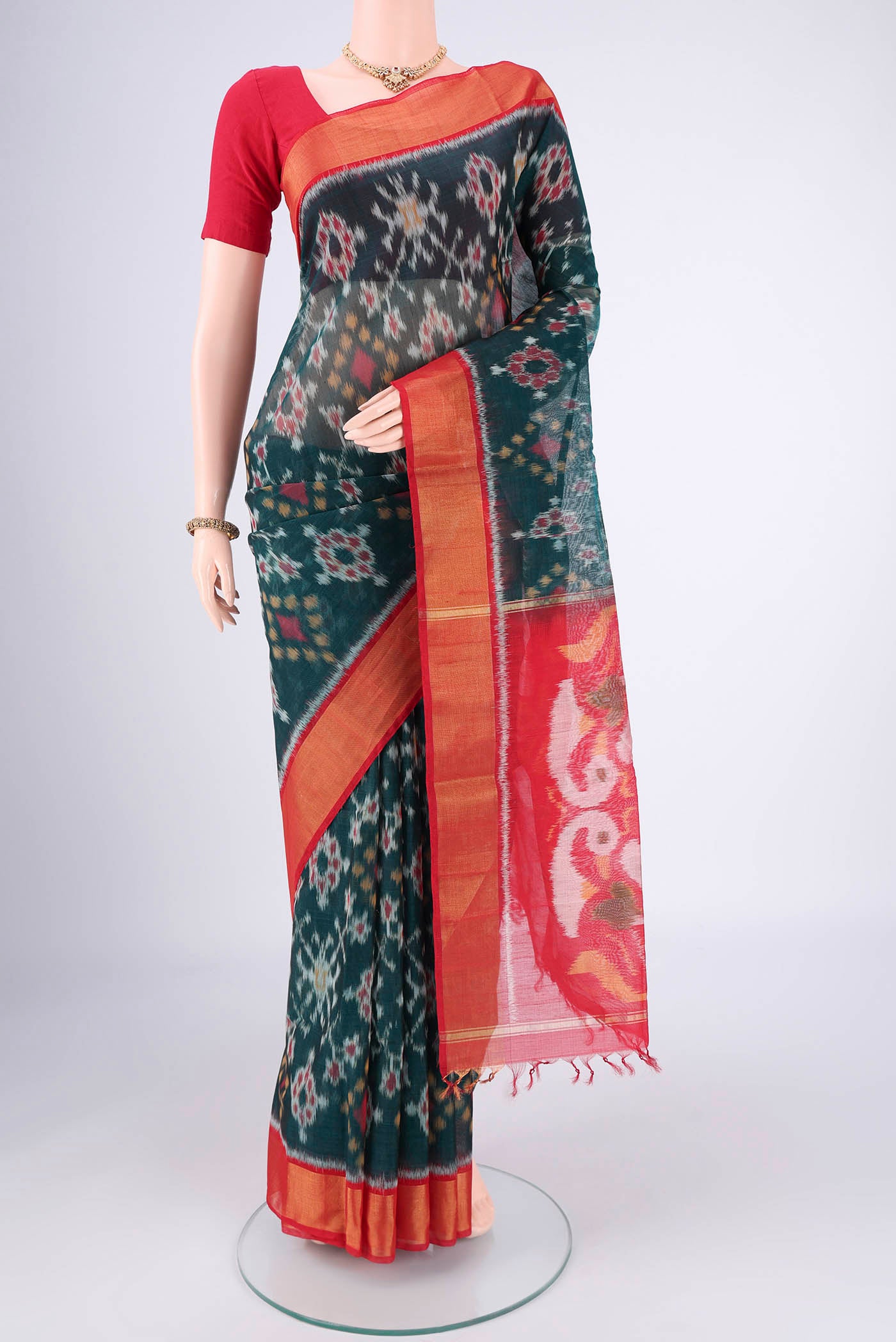 Bottle Green Kora Cotton Saree with Ikat design on the body and Zari Border.  displayed on a mannequin