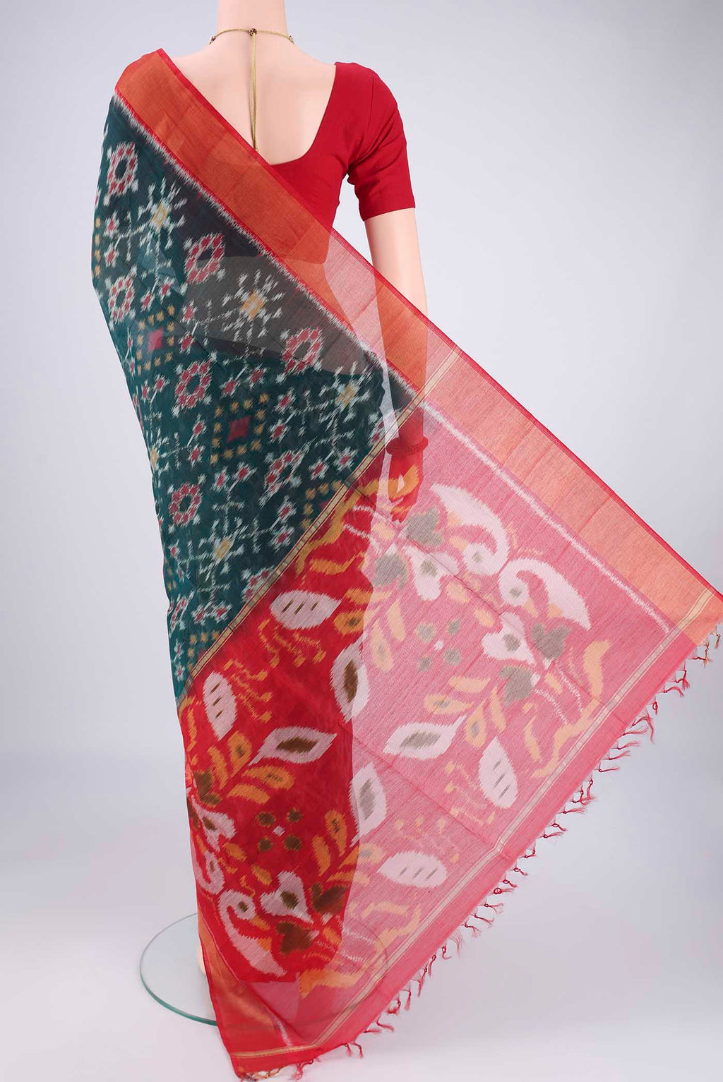 Flat view of Bottle Green Kora Cotton Saree with Ikat design on the body and Zari Border. 