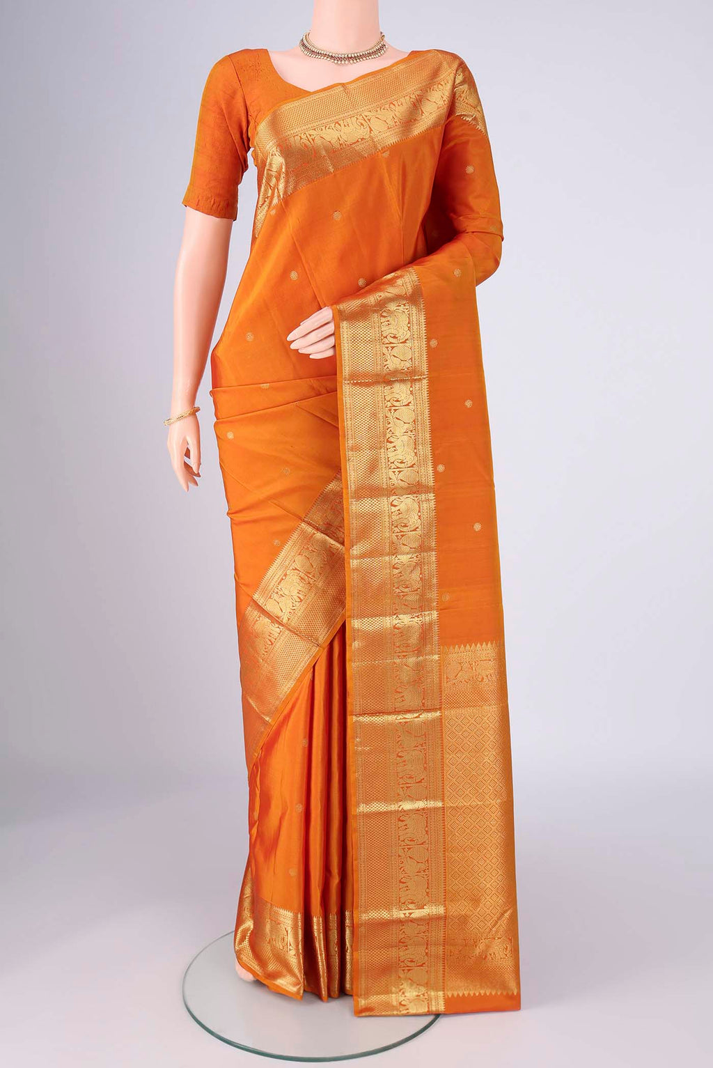 Brick Orange Kanchipuram Silk Saree with Zari Butta on the body and Zari Border.  displayed on a mannequin