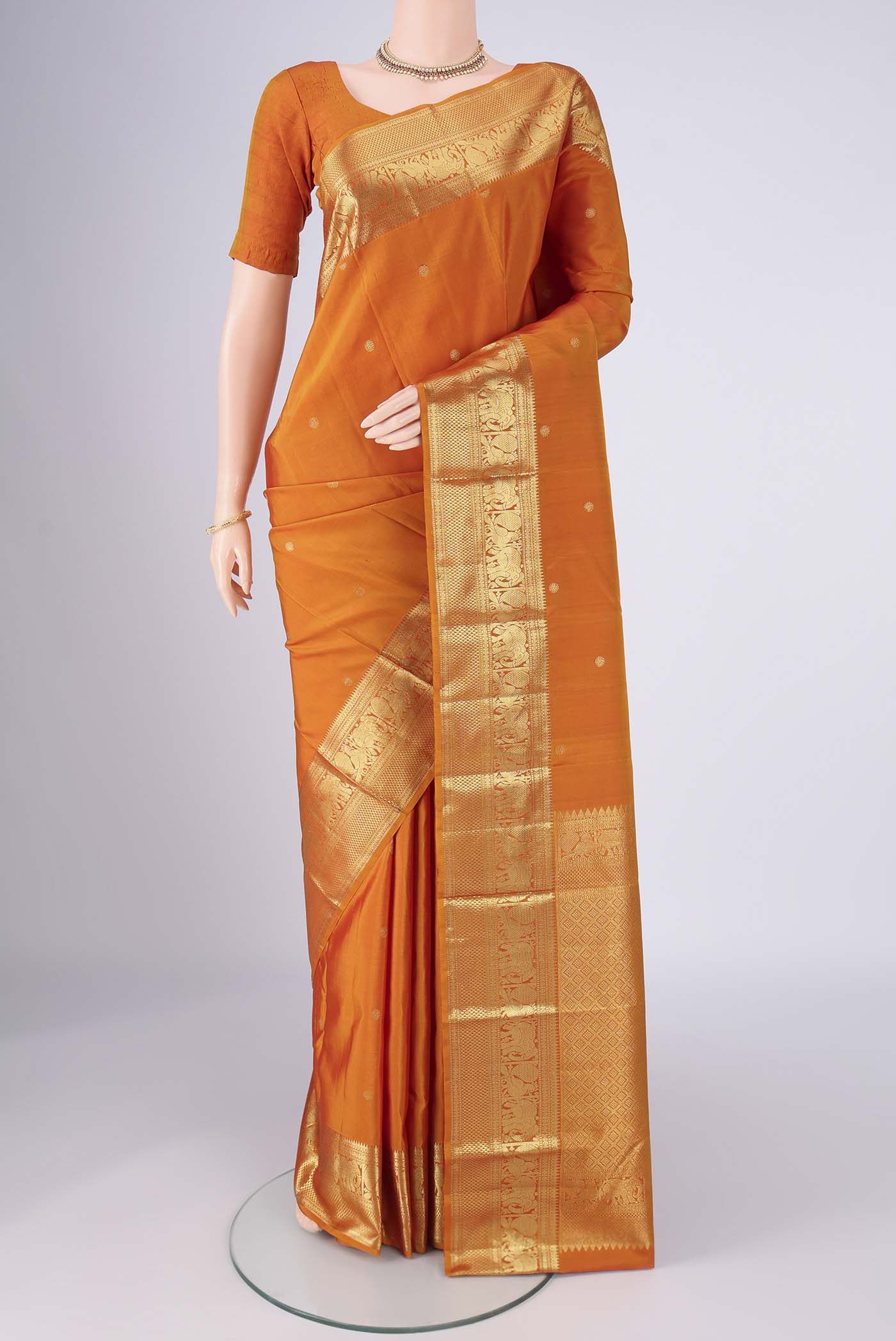 Brick Orange Kanchipuram Silk Saree with Zari Butta on the body and Zari Border.  displayed on a mannequin