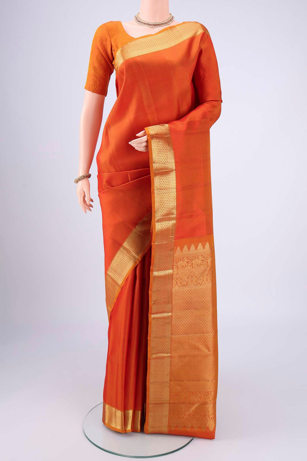 Rust Kanjivaram Silk Saree with Jacquard design on the body and Zari Border.  displayed on a mannequin