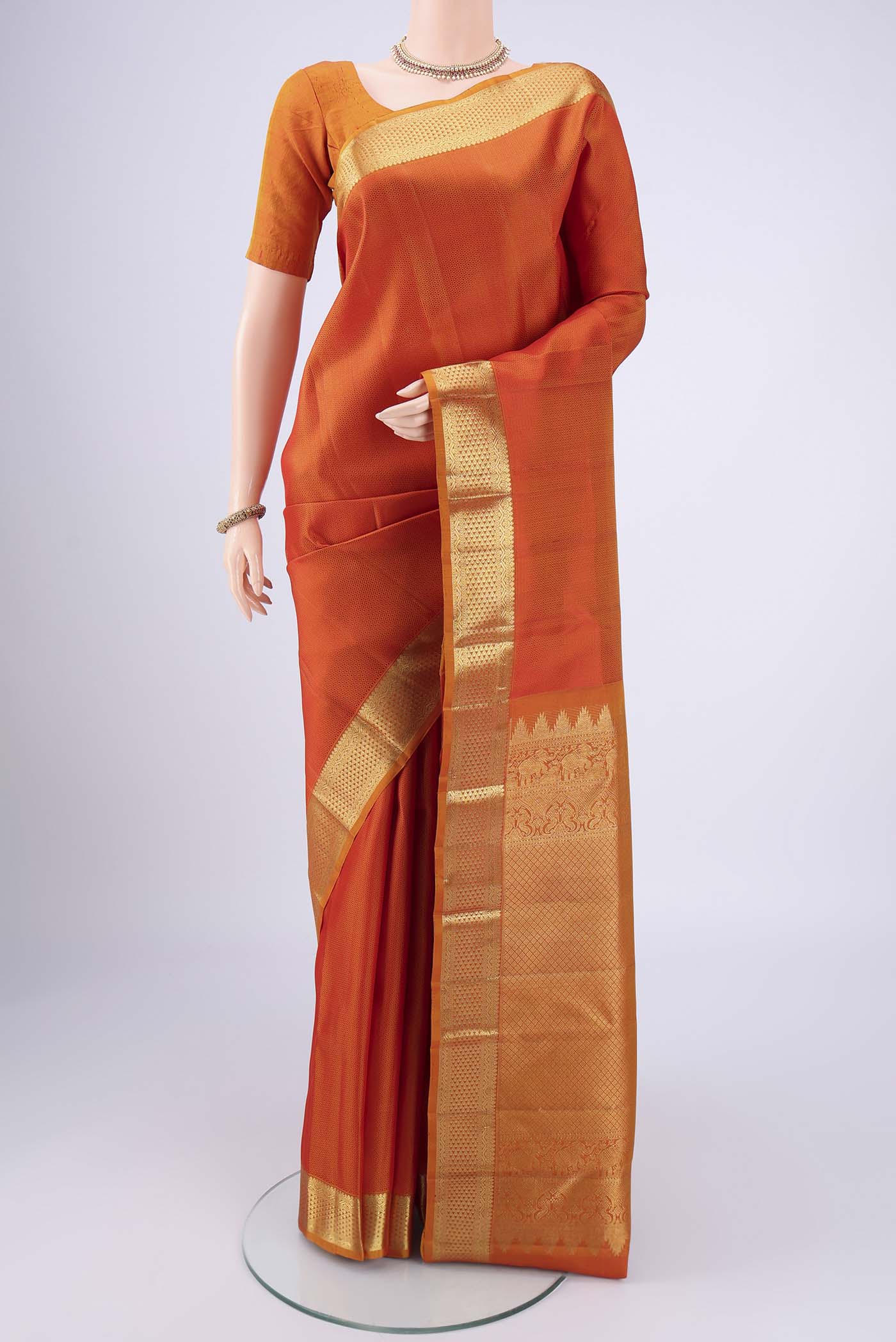 Rust Kanjivaram Silk Saree with Jacquard design on the body and Zari Border.  displayed on a mannequin