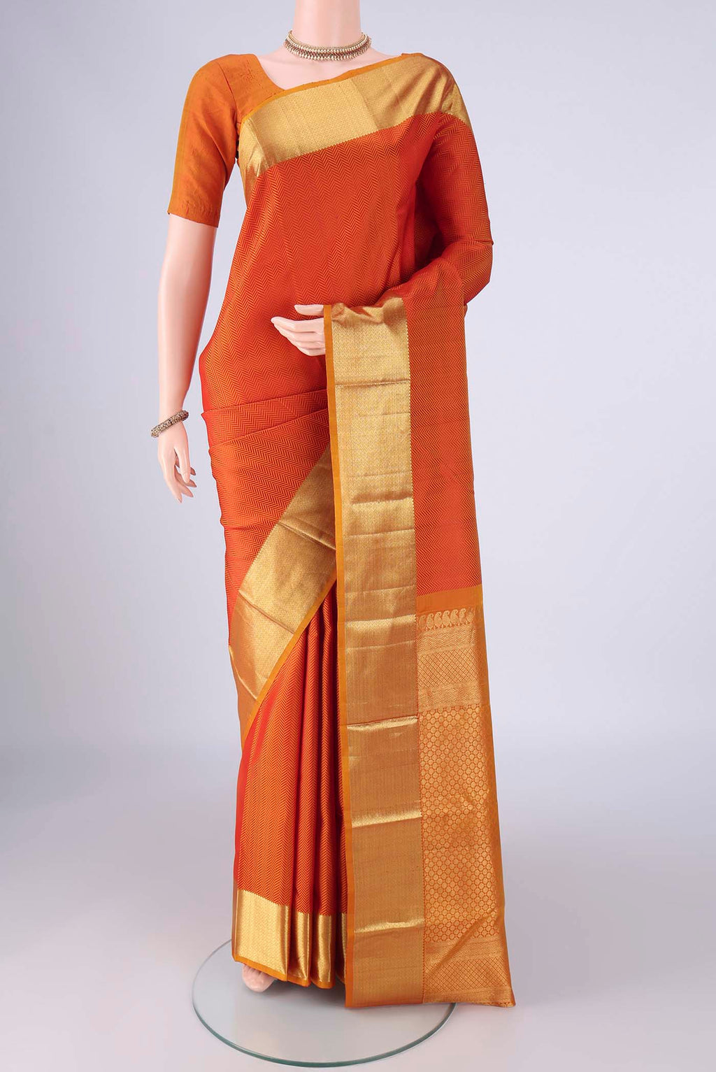 Orange Kanjivaram Silk Saree with Jacquard design on the body and Zari Border.  displayed on a mannequin