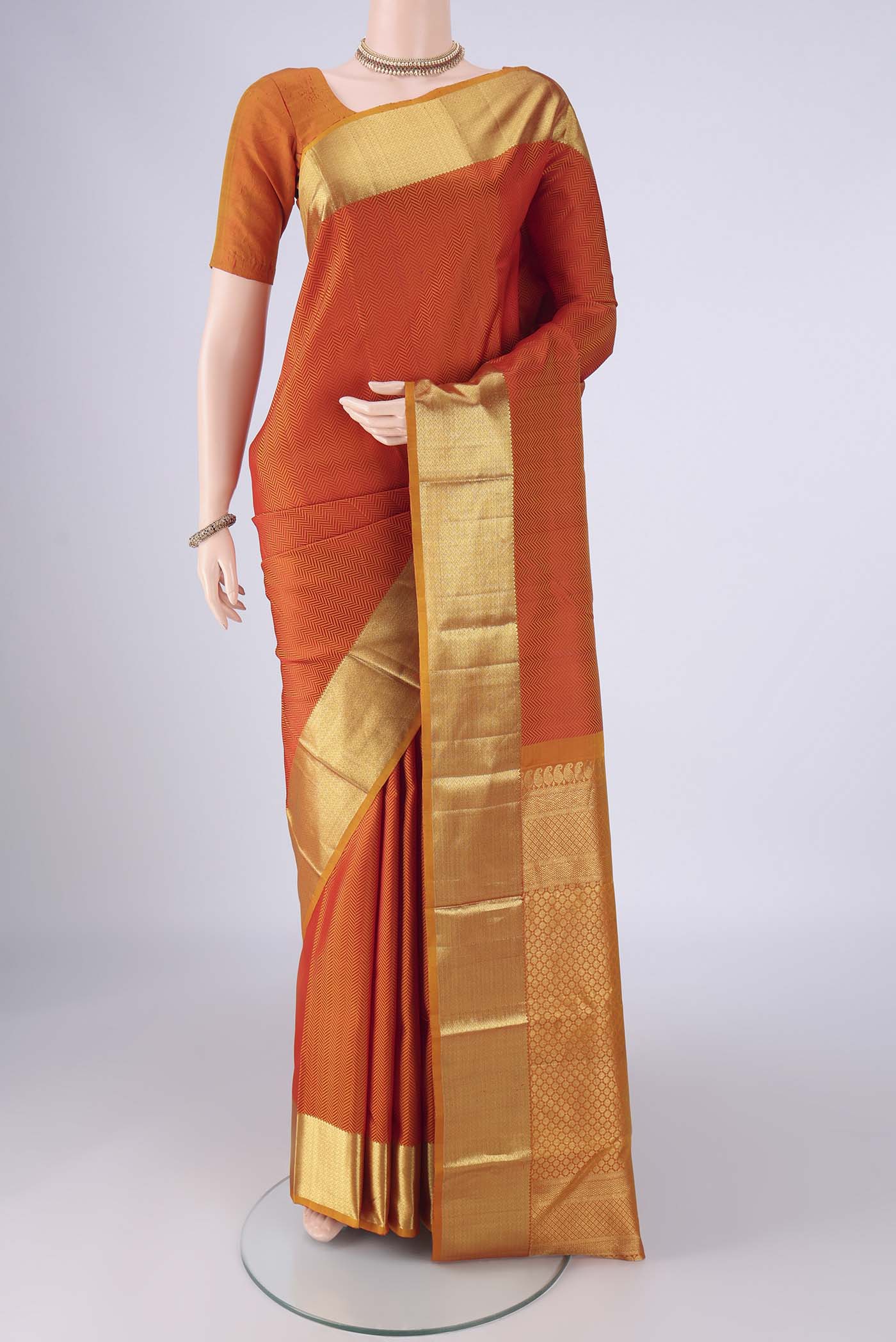 Orange Kanjivaram Silk Saree with Jacquard design on the body and Zari Border.  displayed on a mannequin