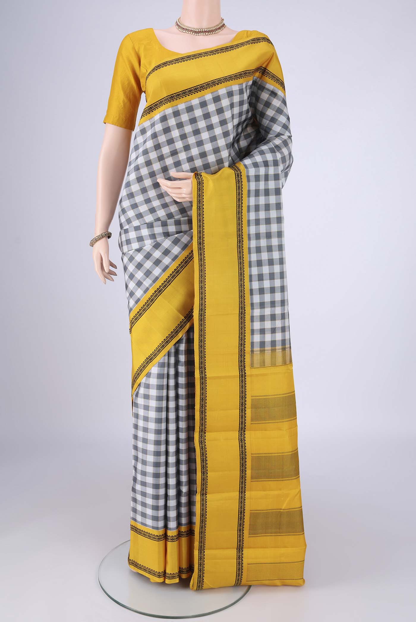 Off White Kanjivaram Silk Saree with Checked design on the body and Thread Border.  displayed on a mannequin