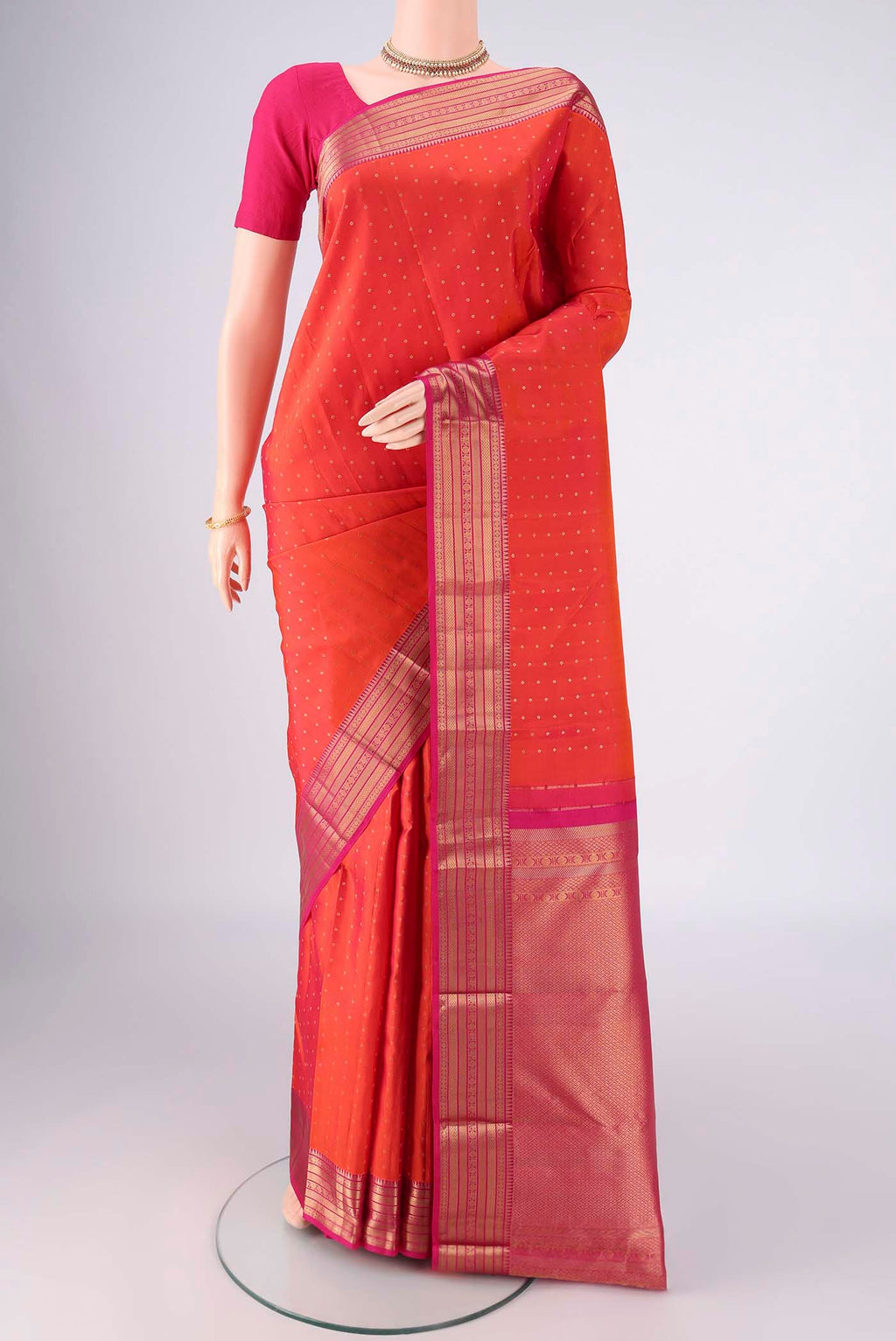 Orange Kanchipuram Silk Saree with Zari Butta on the body and Zari Border.  displayed on a mannequin
