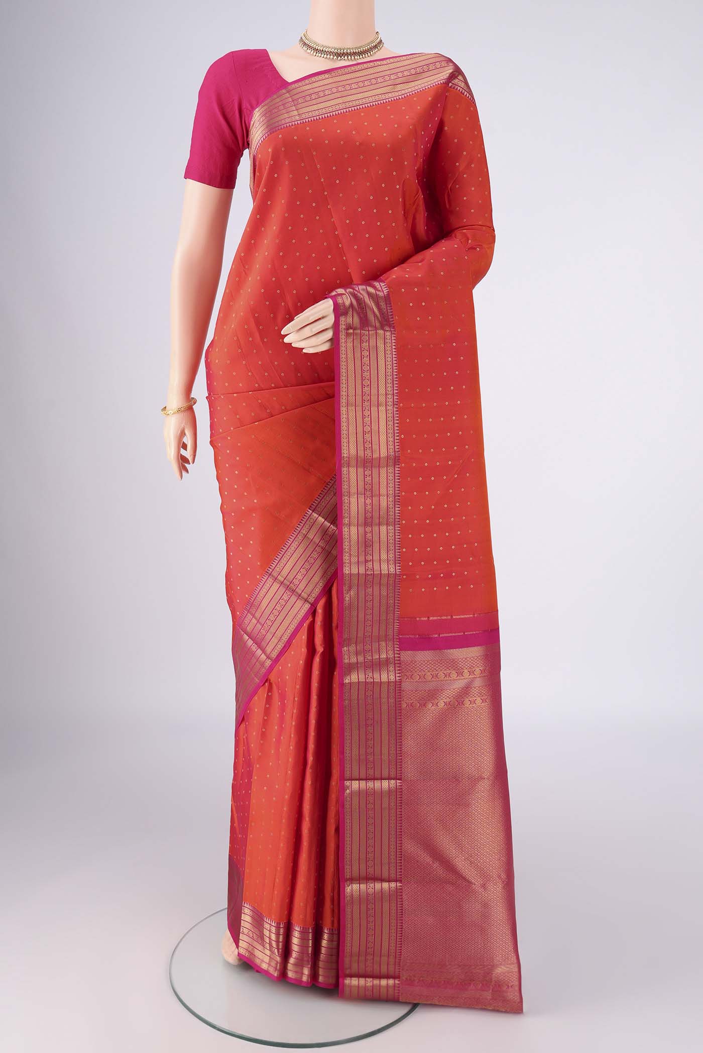 Orange Kanchipuram Silk Saree with Zari Butta on the body and Zari Border.  displayed on a mannequin