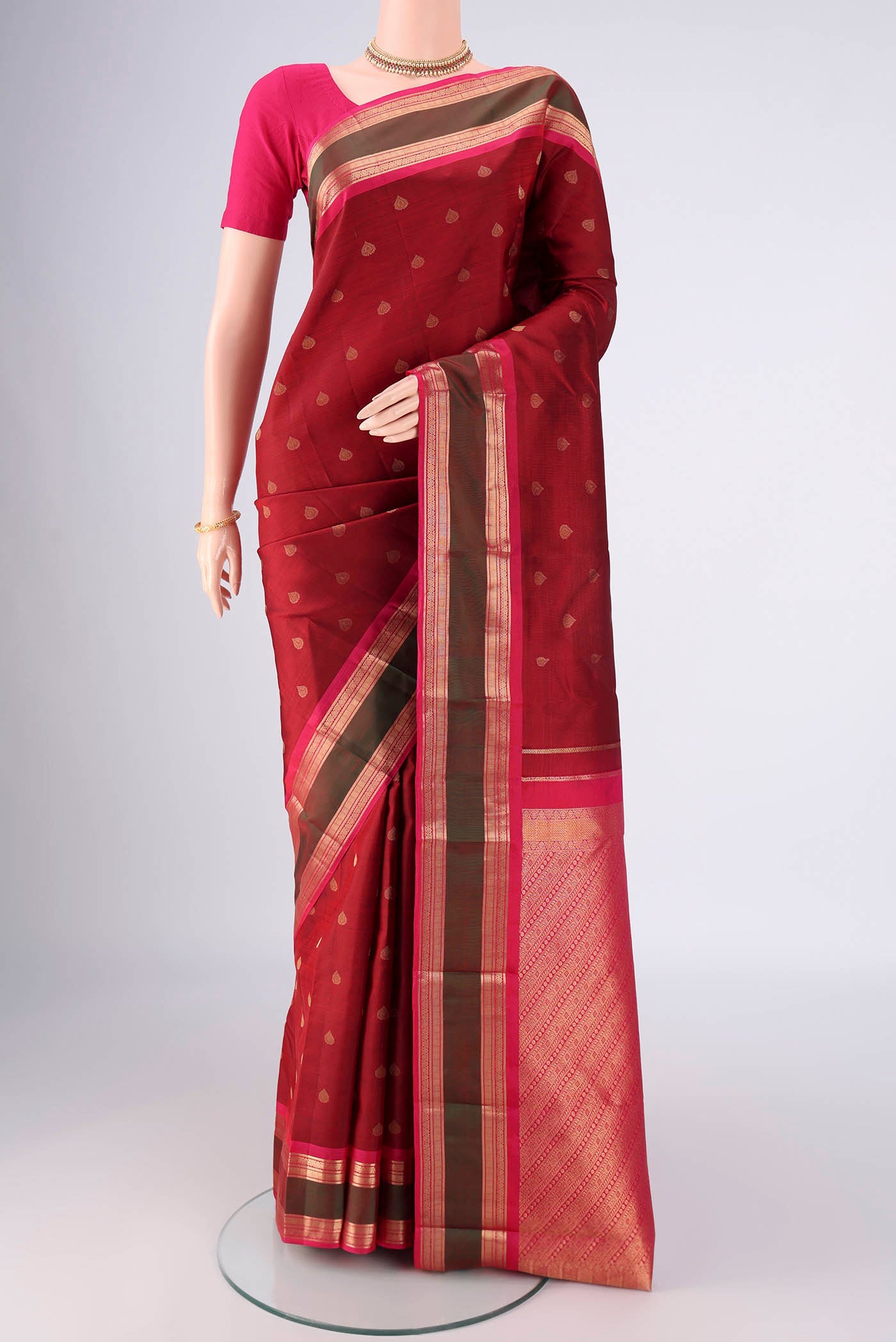 Maroon Kanchipuram Silk Saree with Zari Butta on the body and Zari Border.  displayed on a mannequin