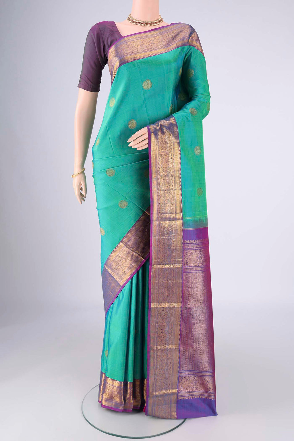 Turquoise Kanjivaram Silk Saree with Zari Butta on the body and Zari Border.  displayed on a mannequin