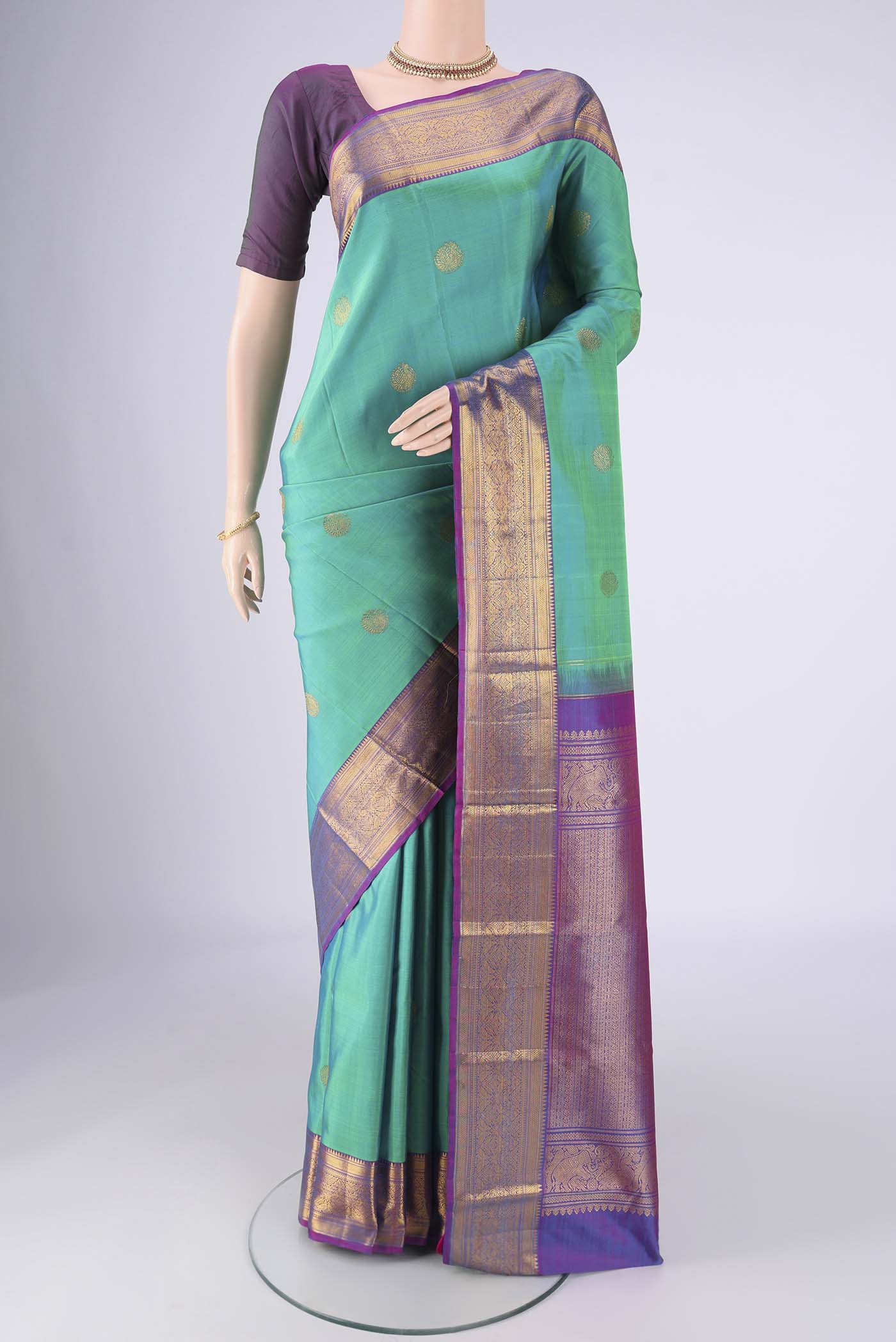 Turquoise Kanjivaram Silk Saree with Zari Butta on the body and Zari Border.  displayed on a mannequin