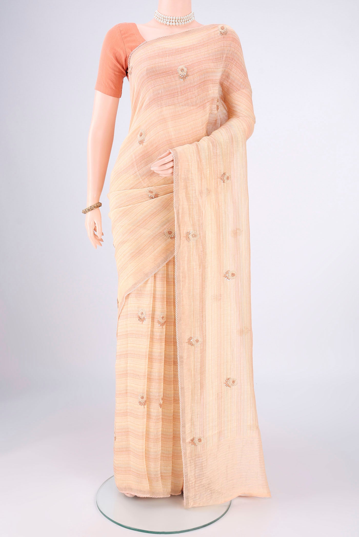 Golden Peach Linen Saree with Embroidery on the body and Lace Border.  displayed on a mannequin
