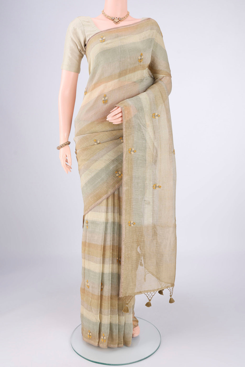 Sage Green Linen Saree with Embroidery on the body and Lace Border.  displayed on a mannequin