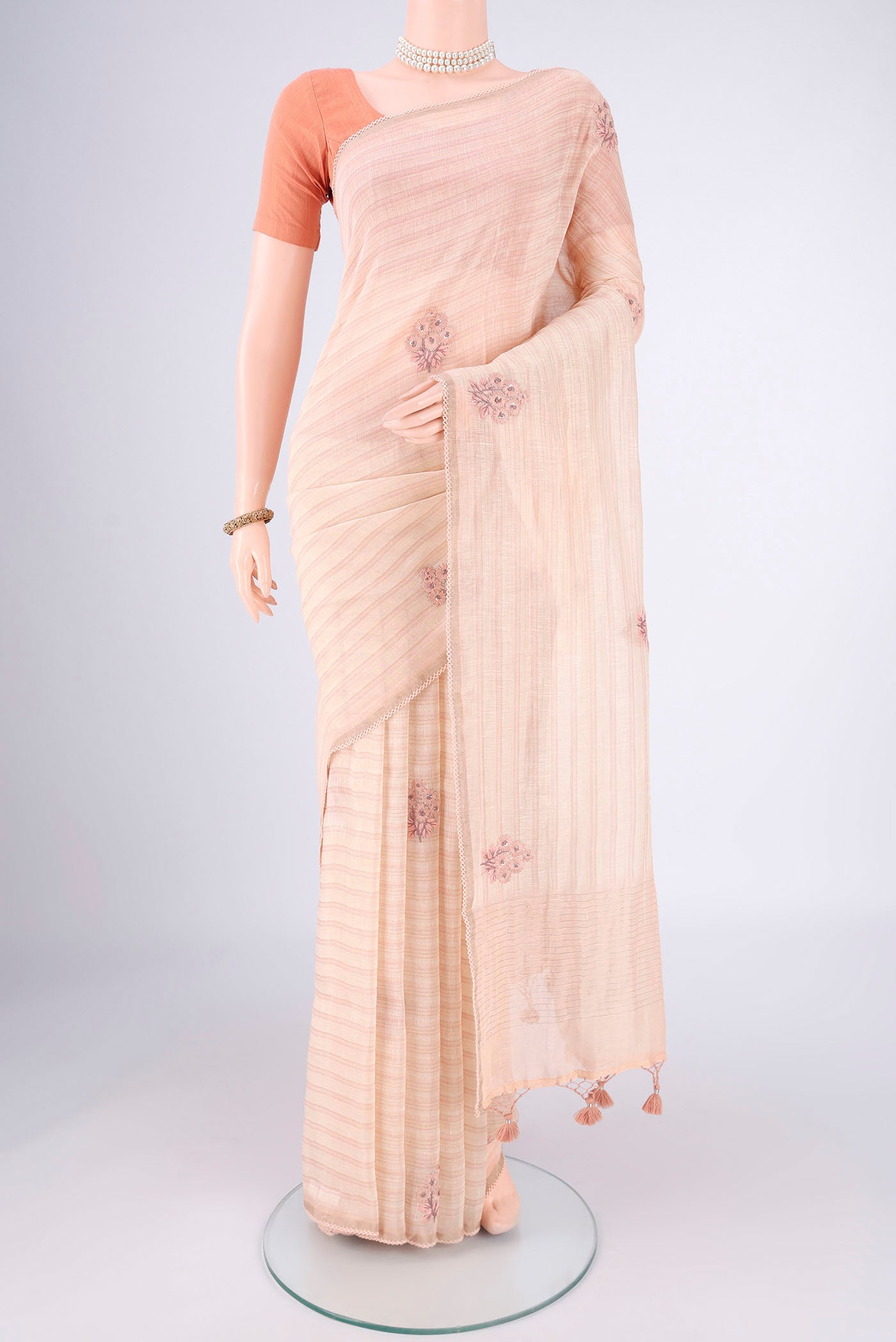 Golden Peach Linen Saree with Embroidery on the body and Lace Border.  displayed on a mannequin