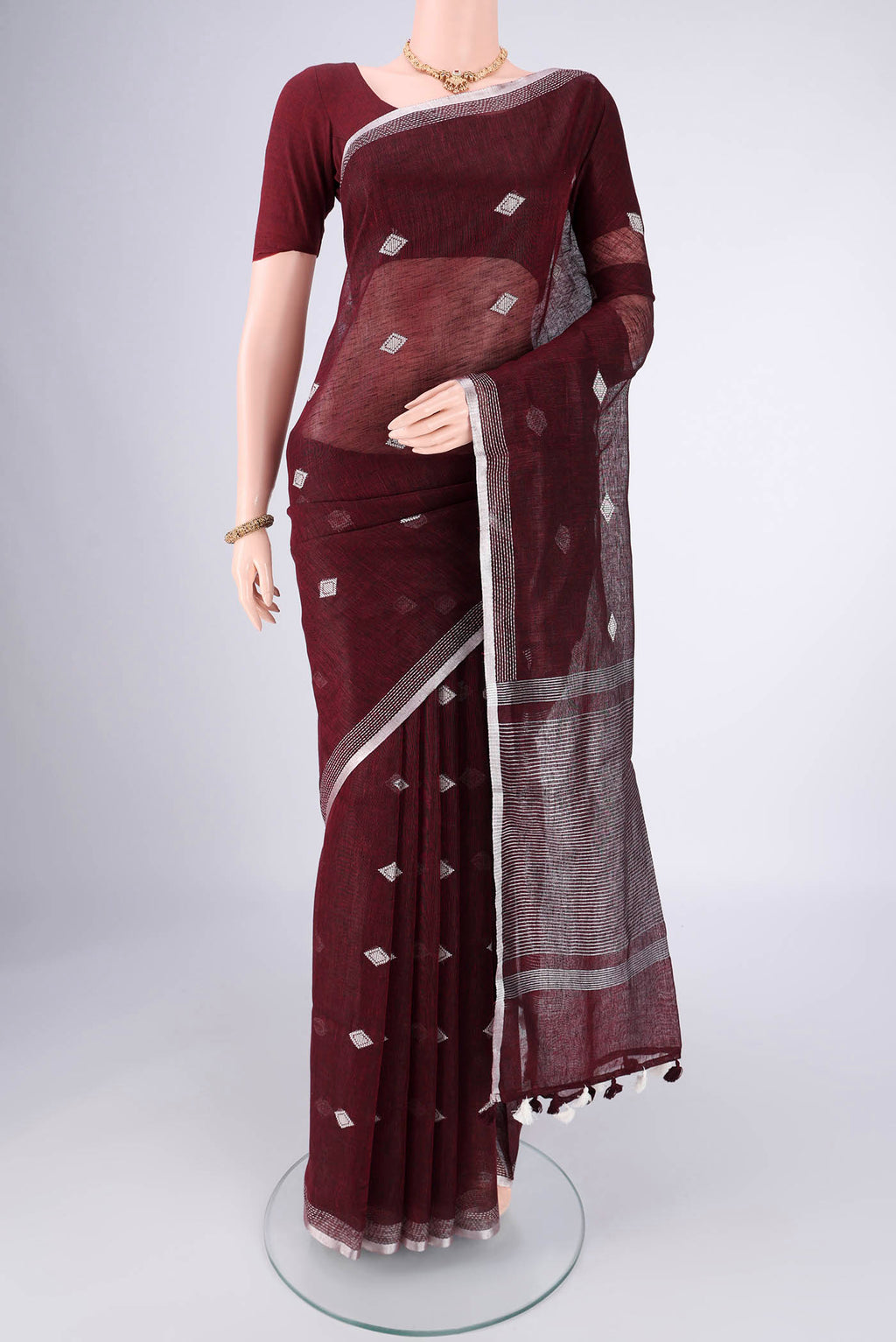 Maroon Linen Cotton Saree with Thread Butta on the body and Zari Border.  displayed on a mannequin