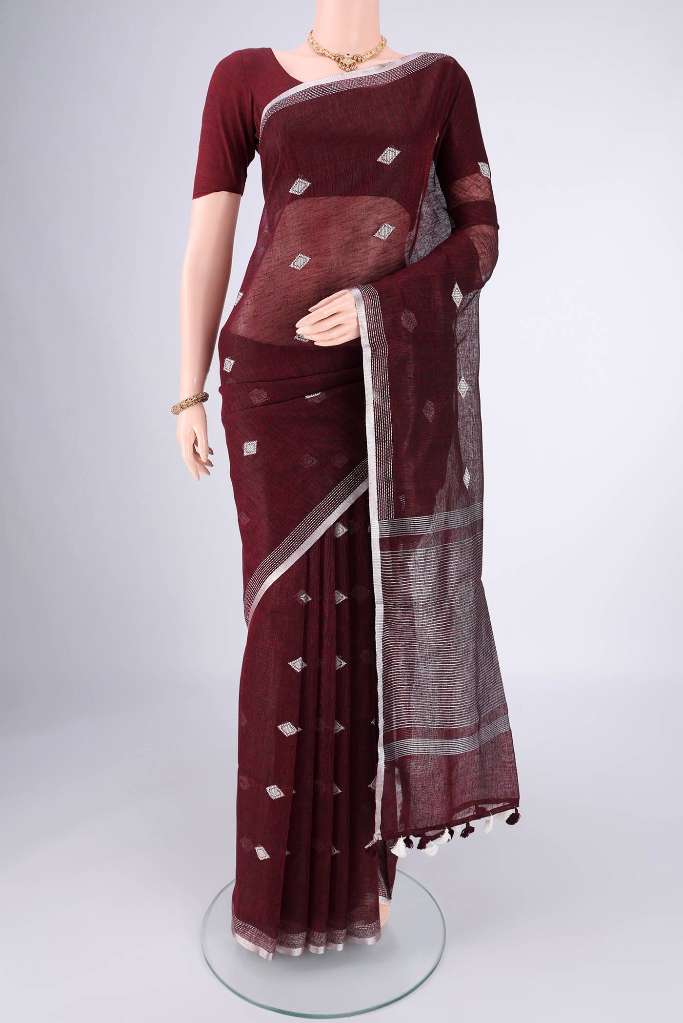 Maroon Linen Cotton Saree with Thread Butta on the body and Zari Border.  displayed on a mannequin