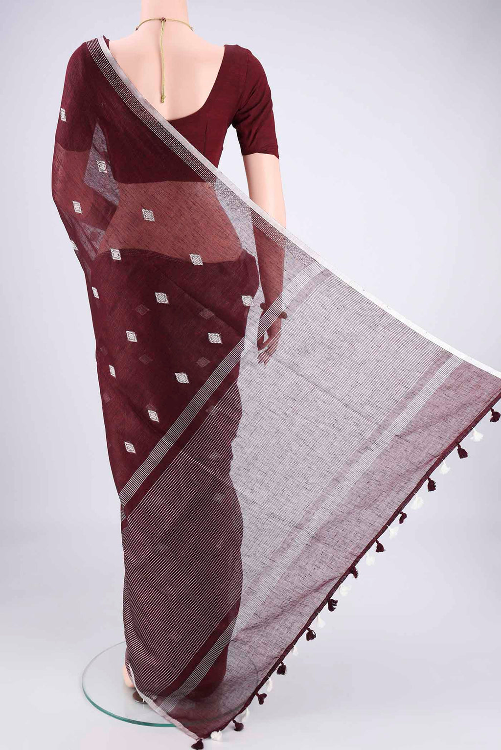 Flat view of Maroon Linen Cotton Saree with Thread Butta on the body and Zari Border. 