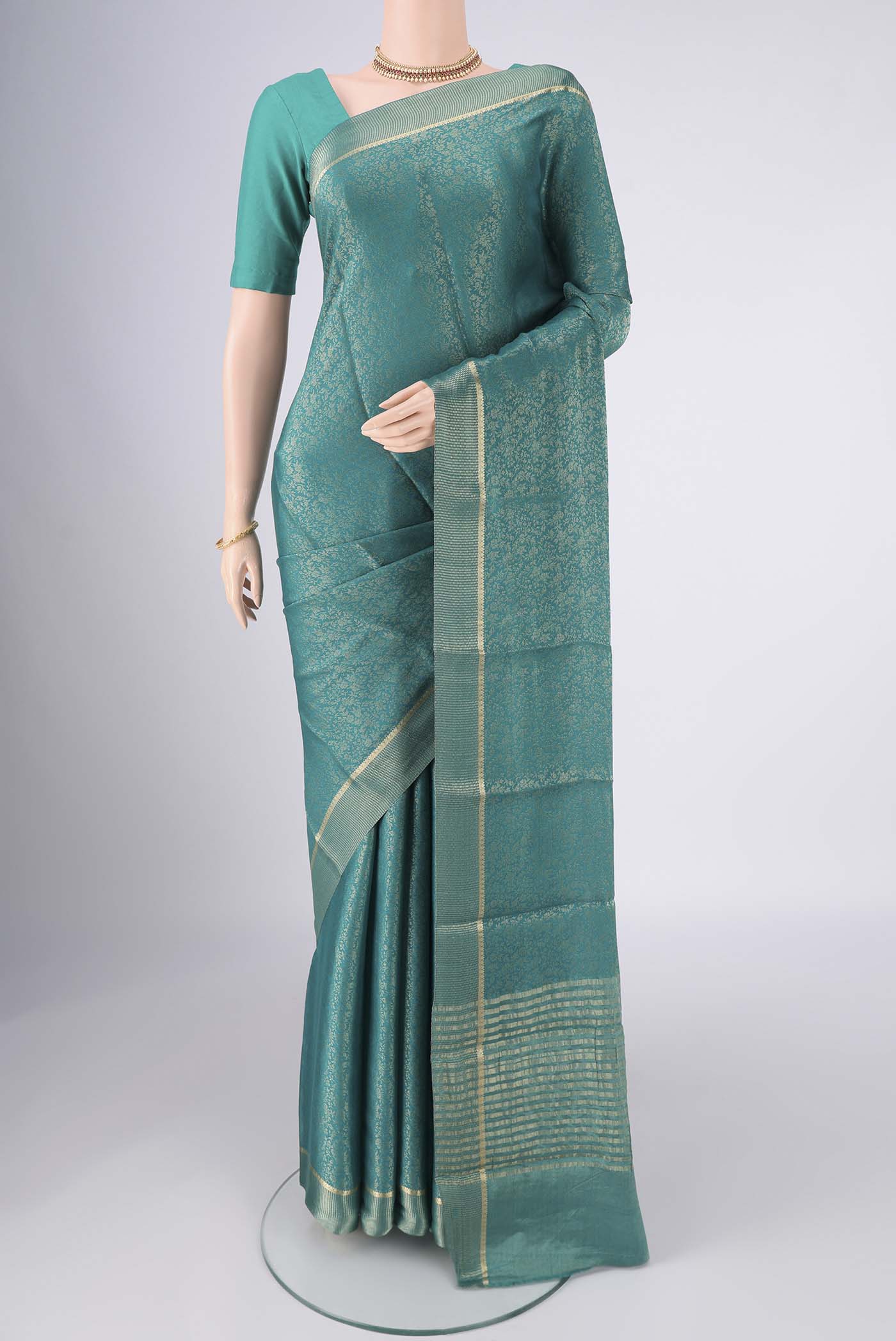 Turquoise Mysore Crepe Saree with Zari Butta on the body and Zari Border.  displayed on a mannequin
